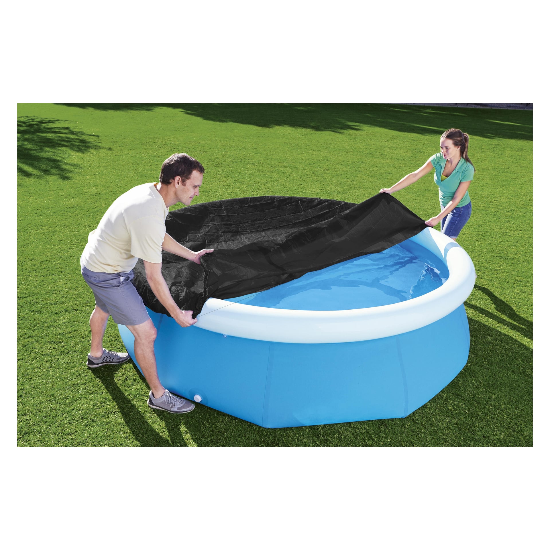 En man och en kvinna täcker en blå uppblåsbar pool fylld med vatten på gräset med hjälp av ett Bestway Round Pool Cover.