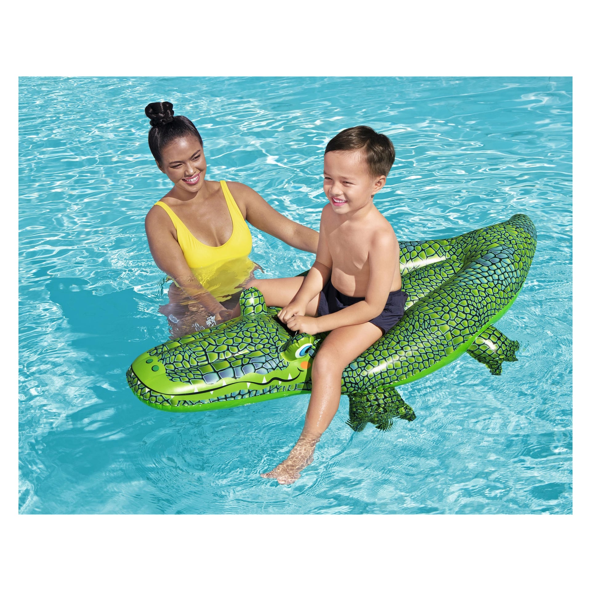 En kvinna i gul baddräkt står i en blå pool, bredvid ett leende barn som rider på Bestway Buddy Crocodile-flotten.