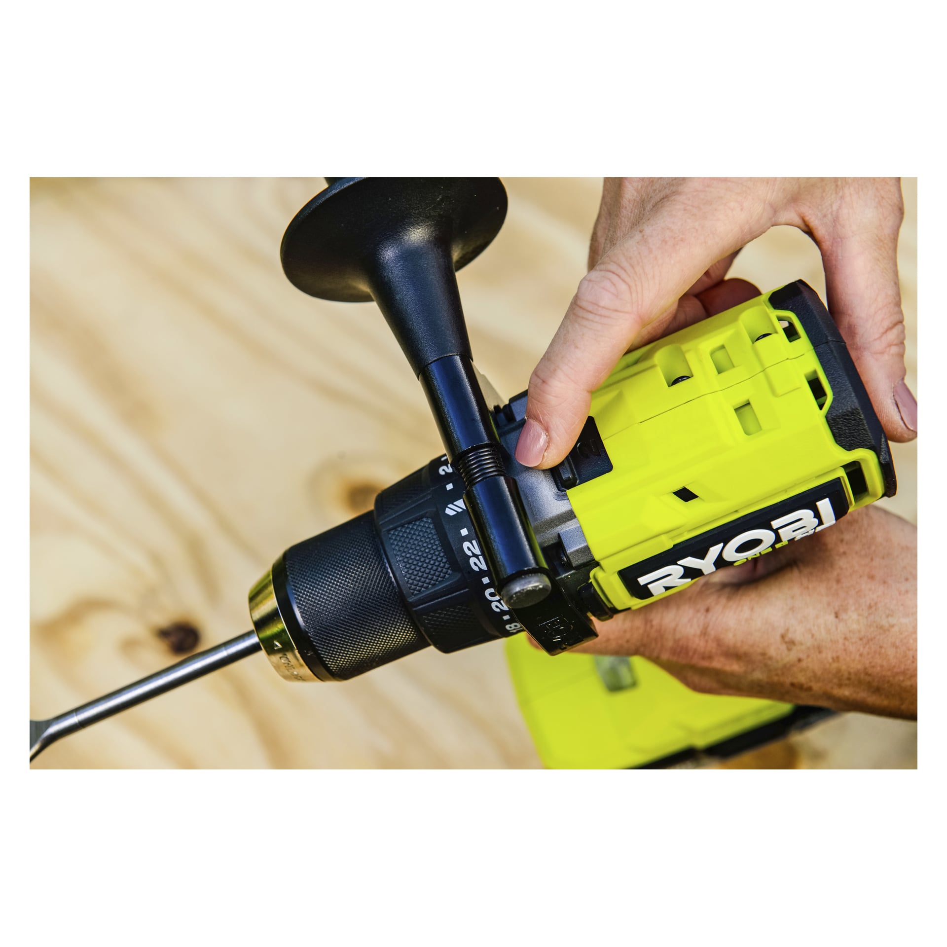 Man justerer håndtaket på en Ryobi One+ HP skrutrekker RPD18X1-0 med en spadebit over en lett treflate.
