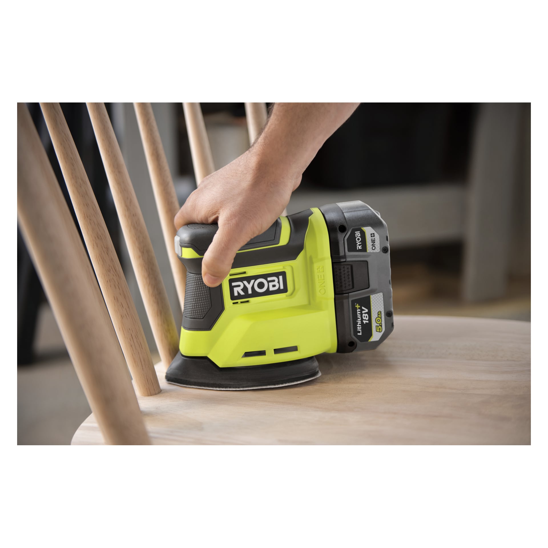 Någon slipar en trästol med en Ryobi One+ Multi-slipare R18PSN-0, spindlar dyker upp i bakgrunden.