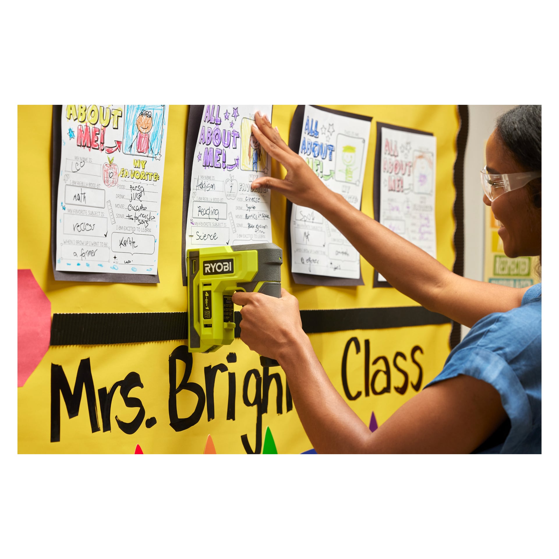 Noen stifter et elevark på en oppslagstavle med teksten «Mrs. Bright's Class» med fargerik Alt om meg! ark med en Ryobi-stiftepistol.