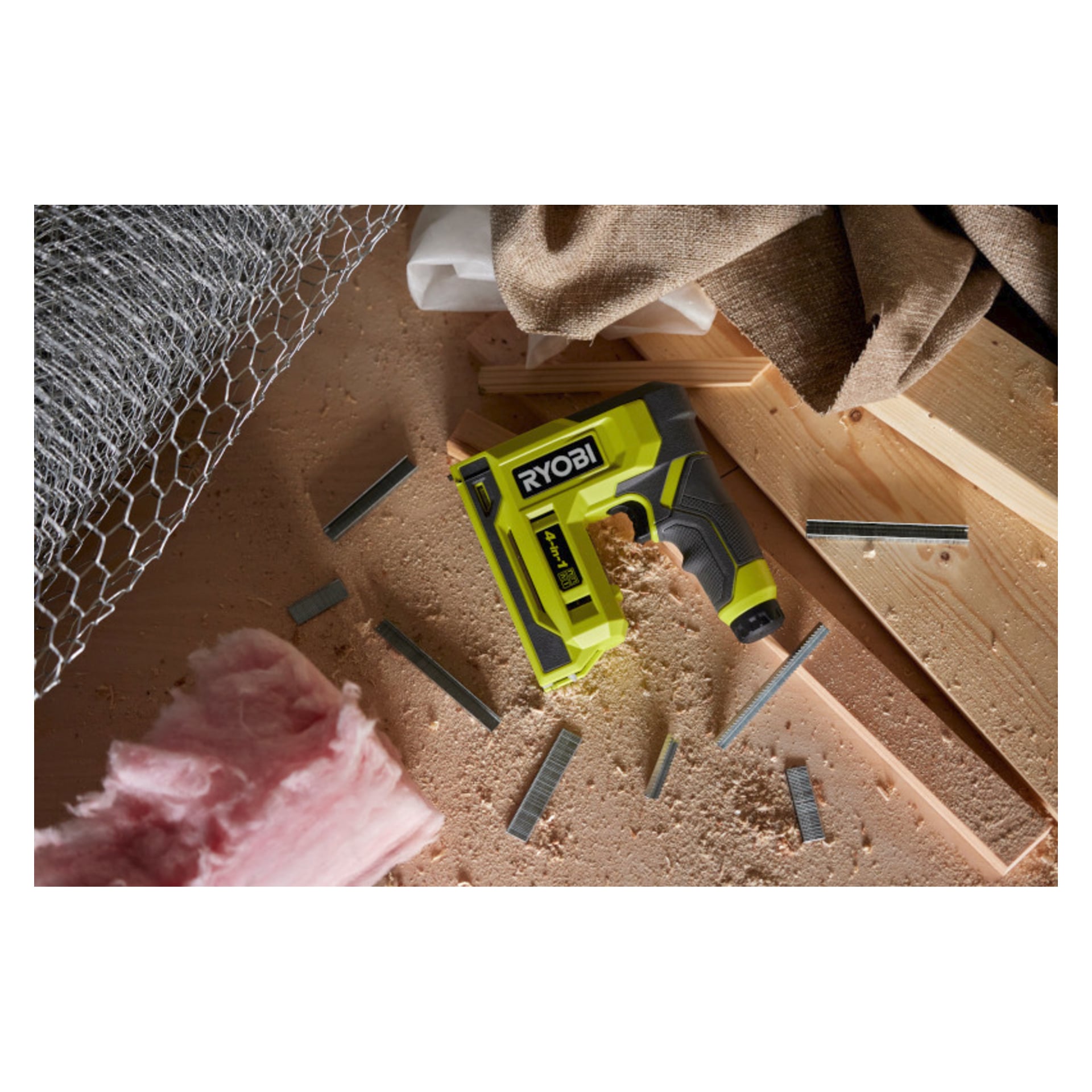 En Ryobi USB Lithium Battery-stiftepistol RST4-0 hviler på tre blant stifter, rosa isolasjon, treplanker, netting og jutestoff.