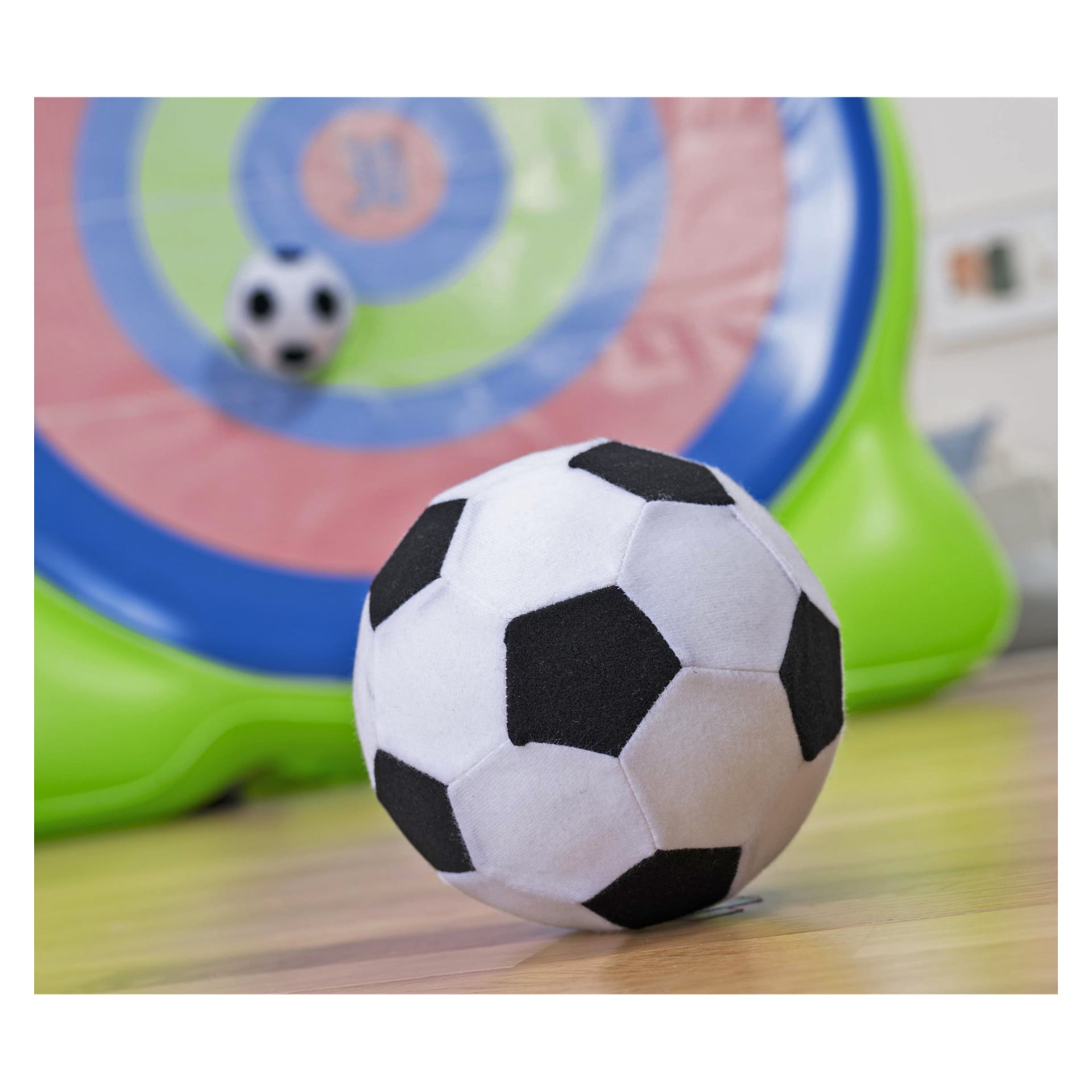 Ett Bestway uppblåsbart dartbräde-Bullseye 2-i-1-spel i trädgården står på ett trägolv med en fotboll och en mindre boll i närheten.
