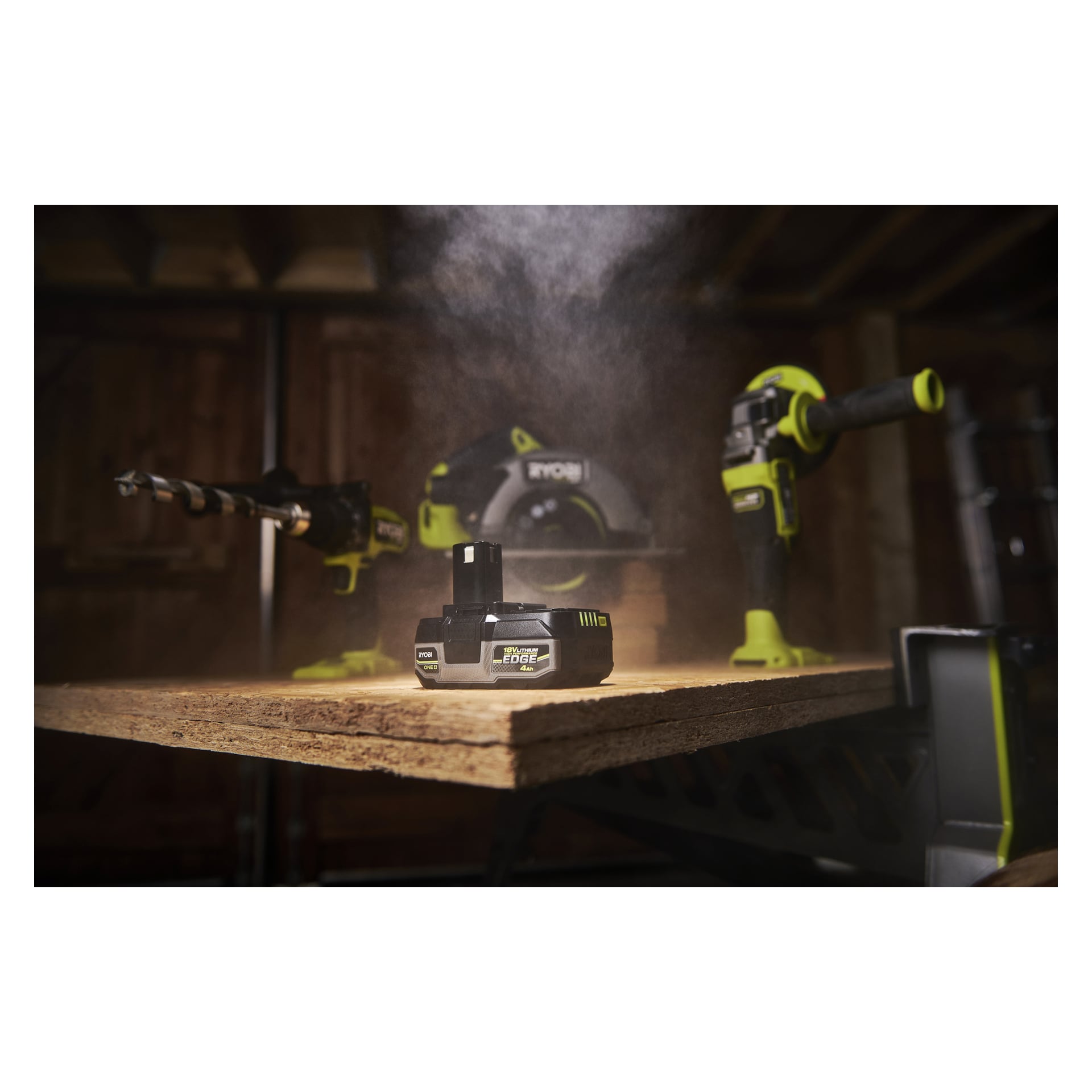 En Ryobi One+ HP Battery Edge RB1840E på en träplanka i en mörk verkstad, Ryobi-verktyg i närheten och diset svävar ovanför.