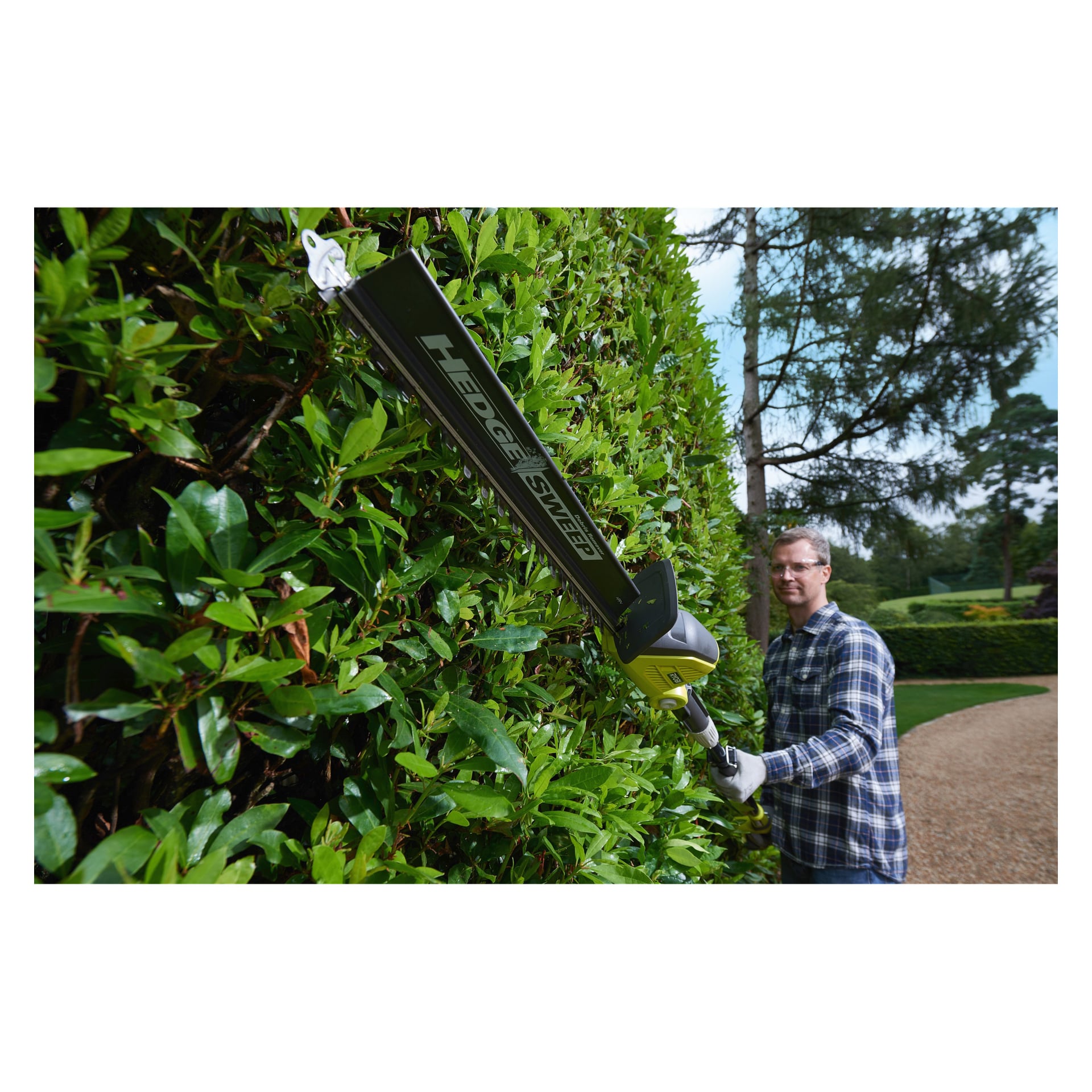 Mit Brille und Handschuhen schneidet man eine hohe Hecke in einem angelegten Garten mit dem Ryobi One+ RPT1845-120 Trimmer.
