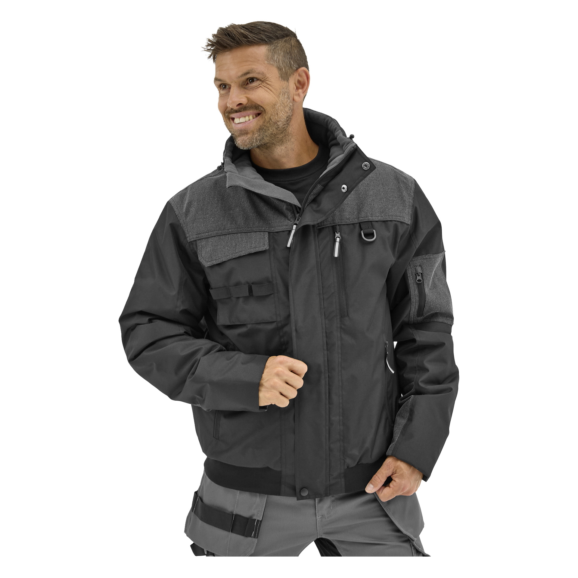 En skäggig man med kort hår ler och ser åt vänster, klädd i den svartgrå Bluewear Johan herrklädda arbetsjackan med många fickor.