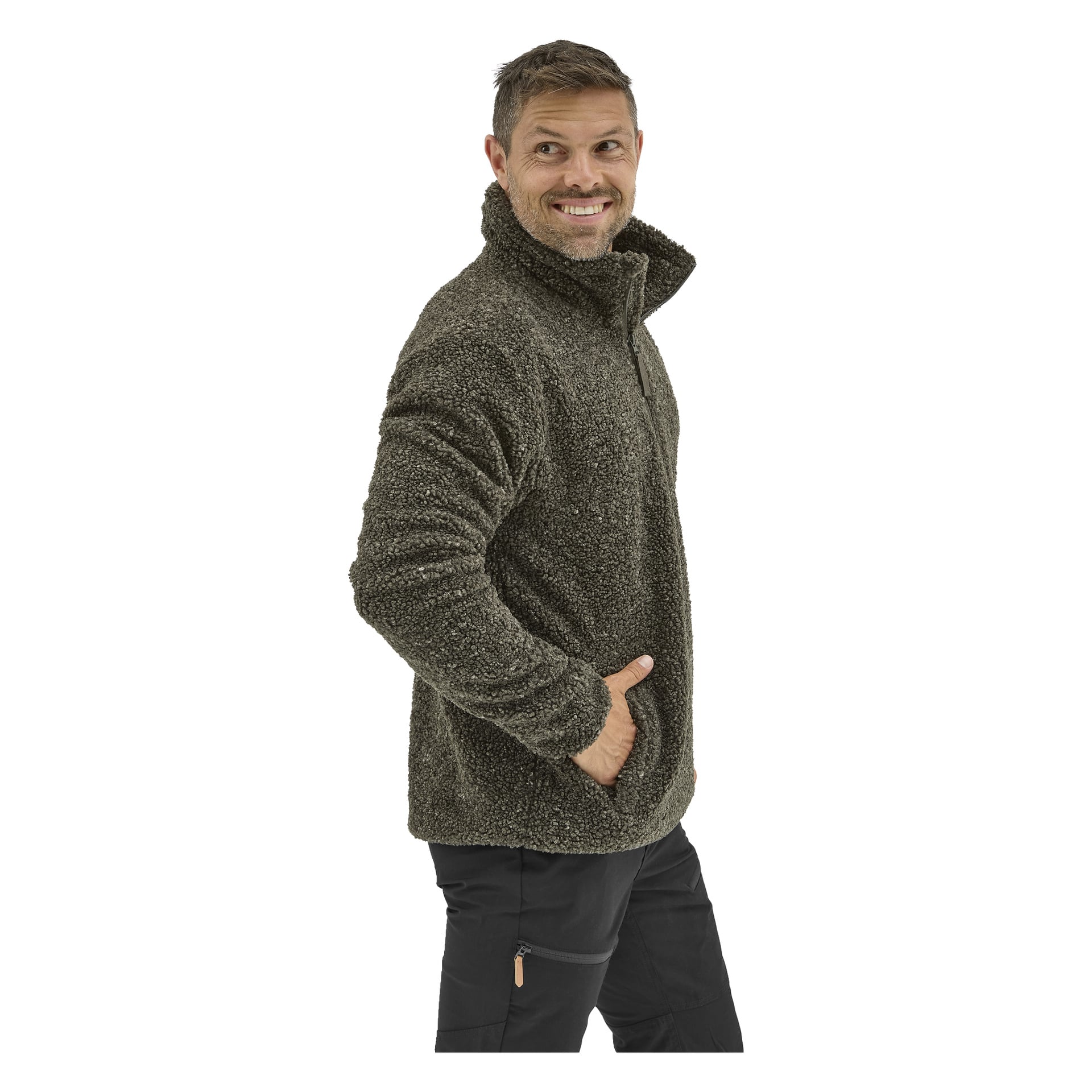 En man i en mörkgrön Kayoba Outdoor Men's jackett och svarta byxor står på sidan, höger hand i fickan, och ler över axeln.