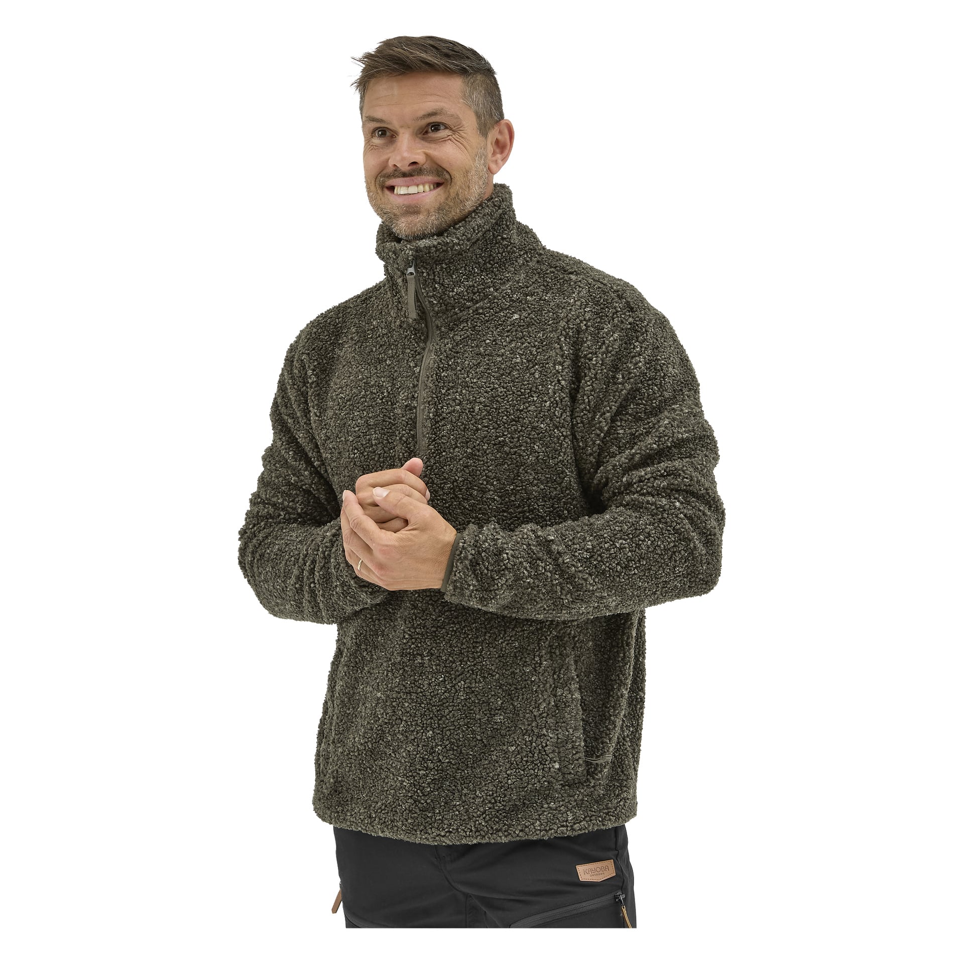 En man med kort hår och välvårdat skägg ler medan han bär en mörkgrön, fluffig Kayoba Outdoor Hamra-jacka, händerna knäppta.
