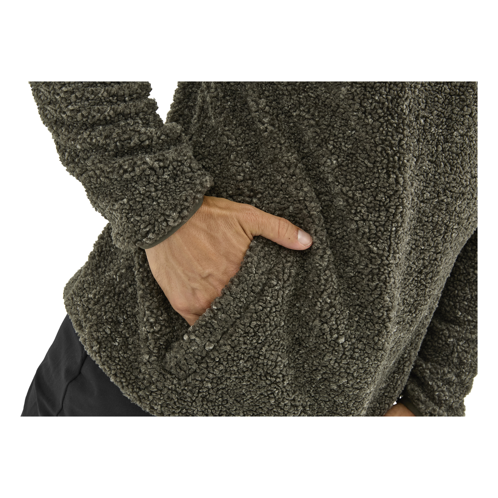 En persons högra hand är delvis instoppad i sidofickan på en mörkgrå kavaj med texturering; svarta byxor, bål och arm syns.