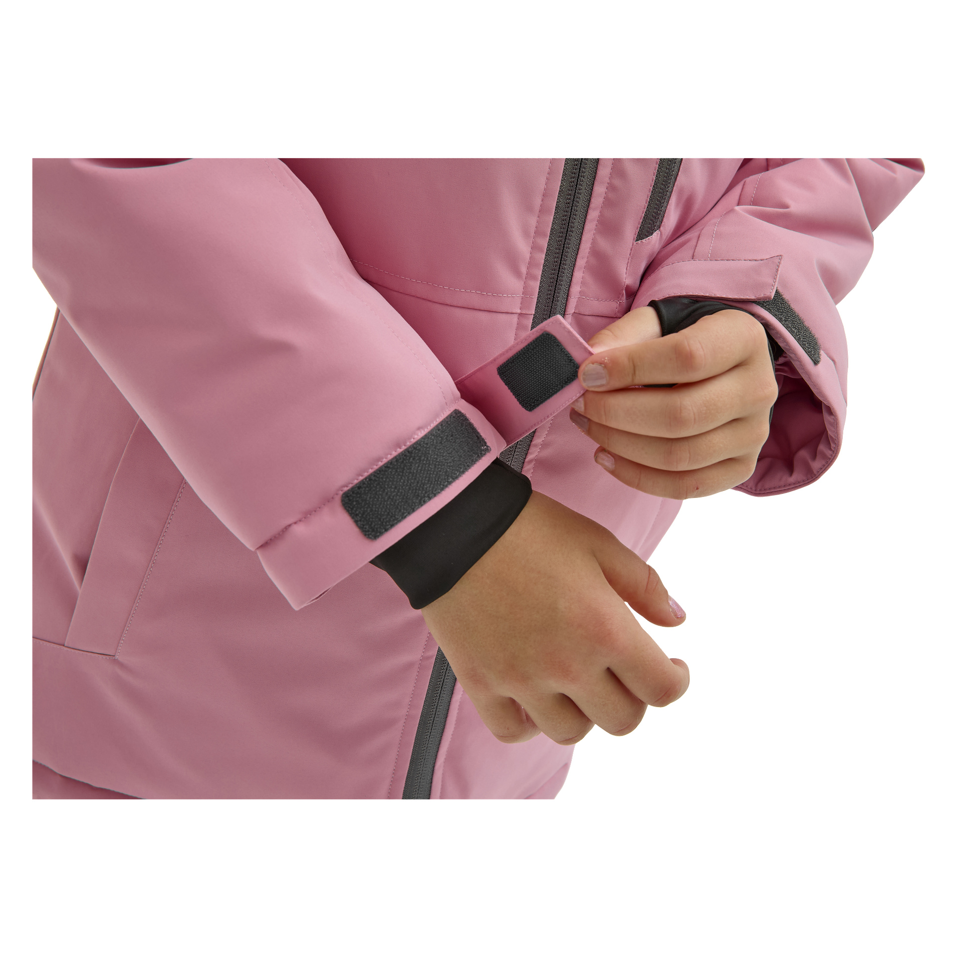 Ett barns händer fäster kardborrebandet på ärmen på en rosa Kayoba Outdoor Children's vinterjacka Kläppen, håller i mudden med ena handen; endast händerna och jackan är synliga.