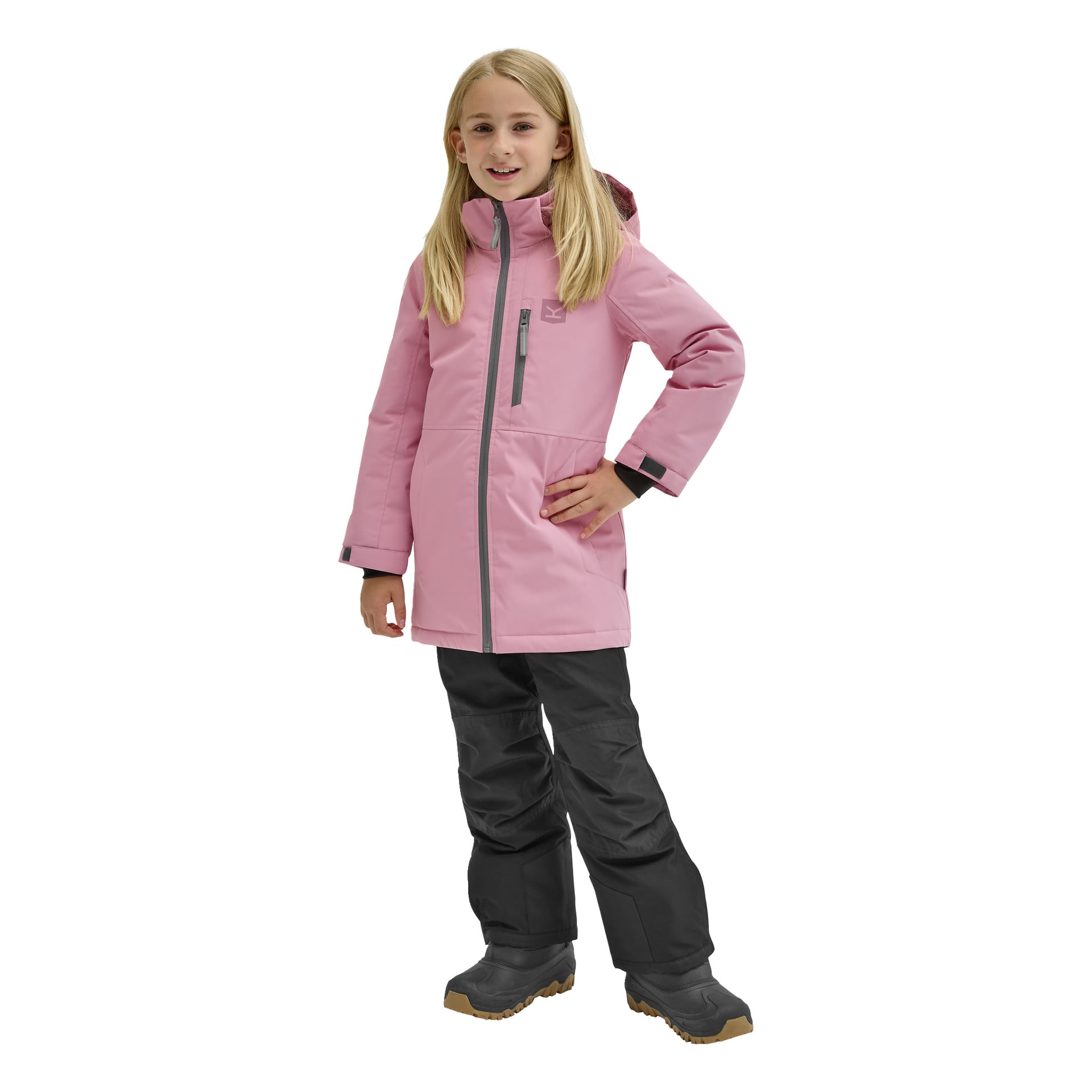Ett barn med långt blont hår bär en rosa huva med "Kayoba Outdoor Children's winter jacket Kläppen" med bröstficka och justerbara manschetter, tillsammans med svarta snöbyxor. Hon står leende, ena handen på höften.