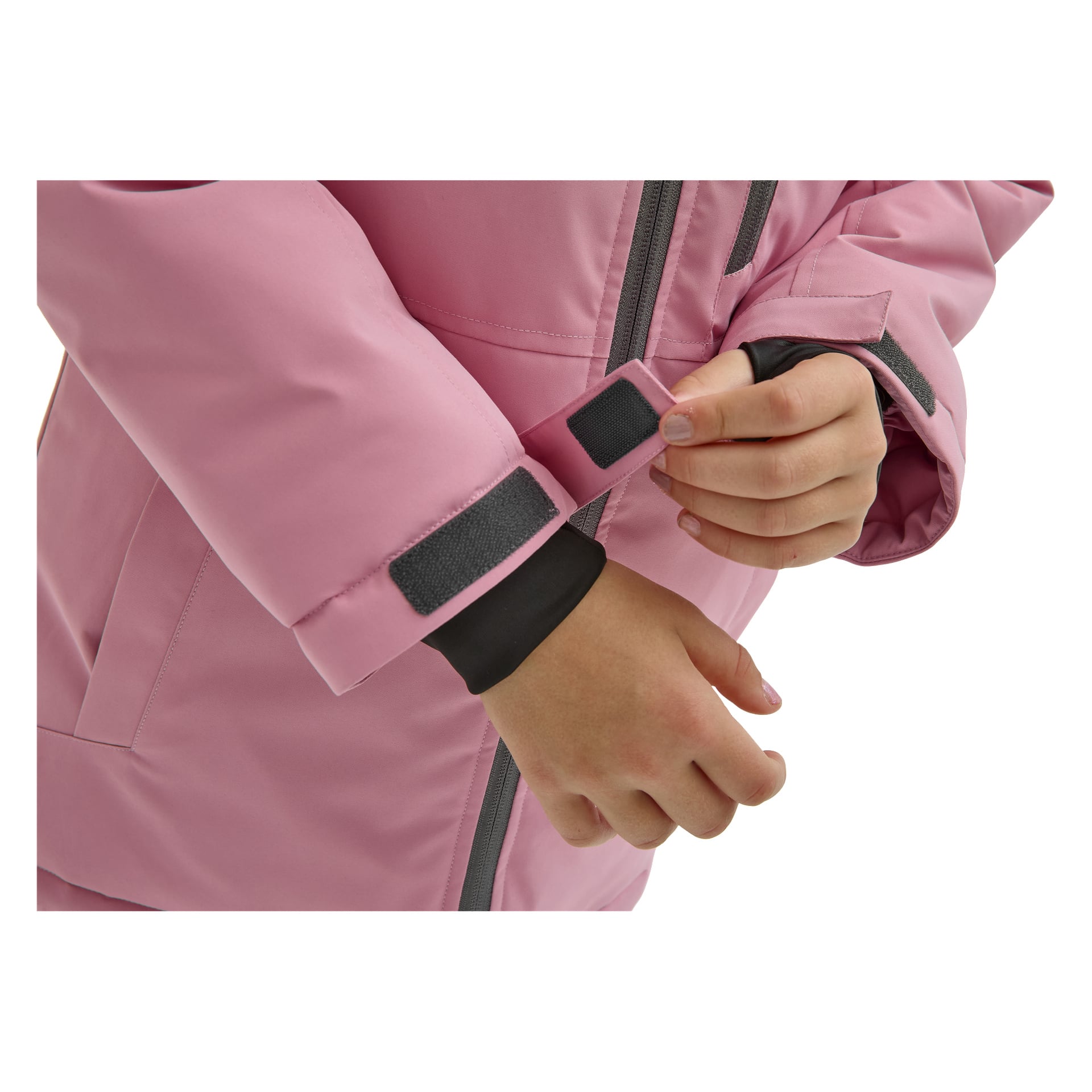 Närbild på en person i en rosa Kayoba Outdoor Children's vinterjacka Kläppen, som använder höger hand för att justera den svarta kardborrebandet på ärmen. Jackan har dragkedja framtill och svarta innerhandschett.