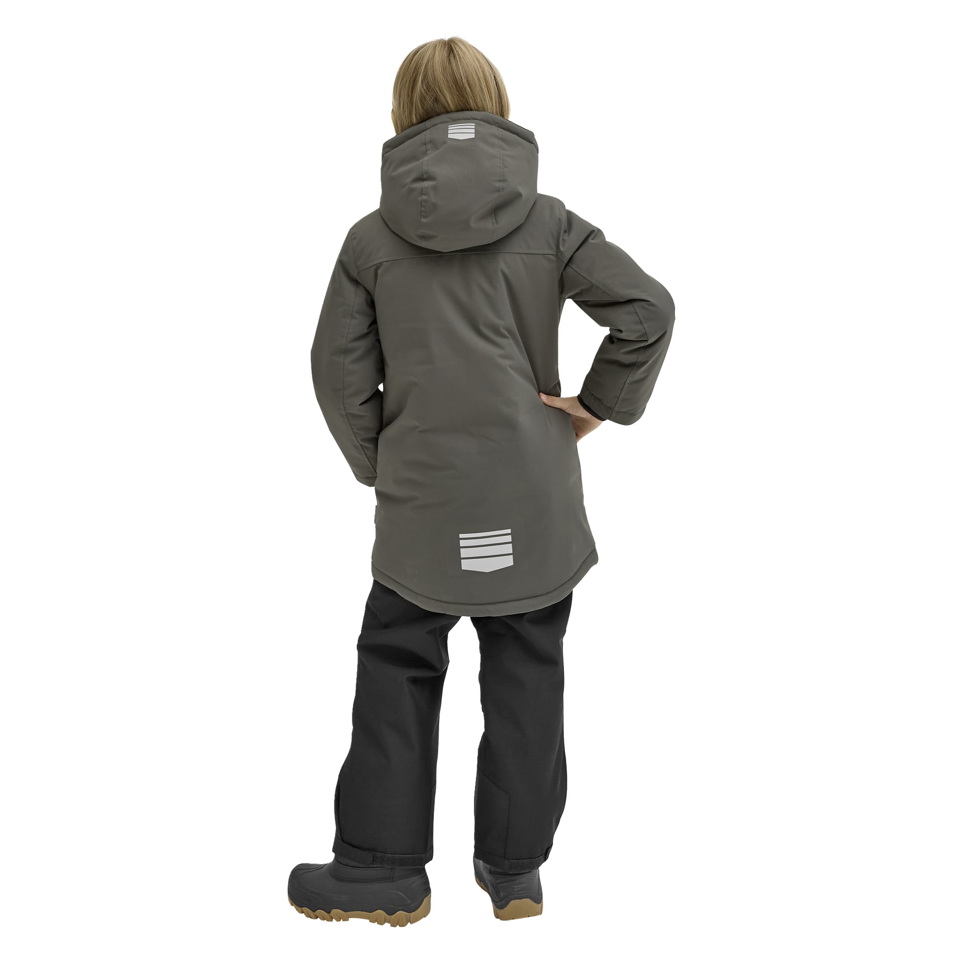 Ett barn står med ryggen mot kameran och bär Kayoba Outdoor Children's vinterjacka Kläppen i grått, som har reflekterande ränder, huva och en hög-låg fåll. Jackan kombineras med svarta snöbyxor. Barnets högra hand är på höften.