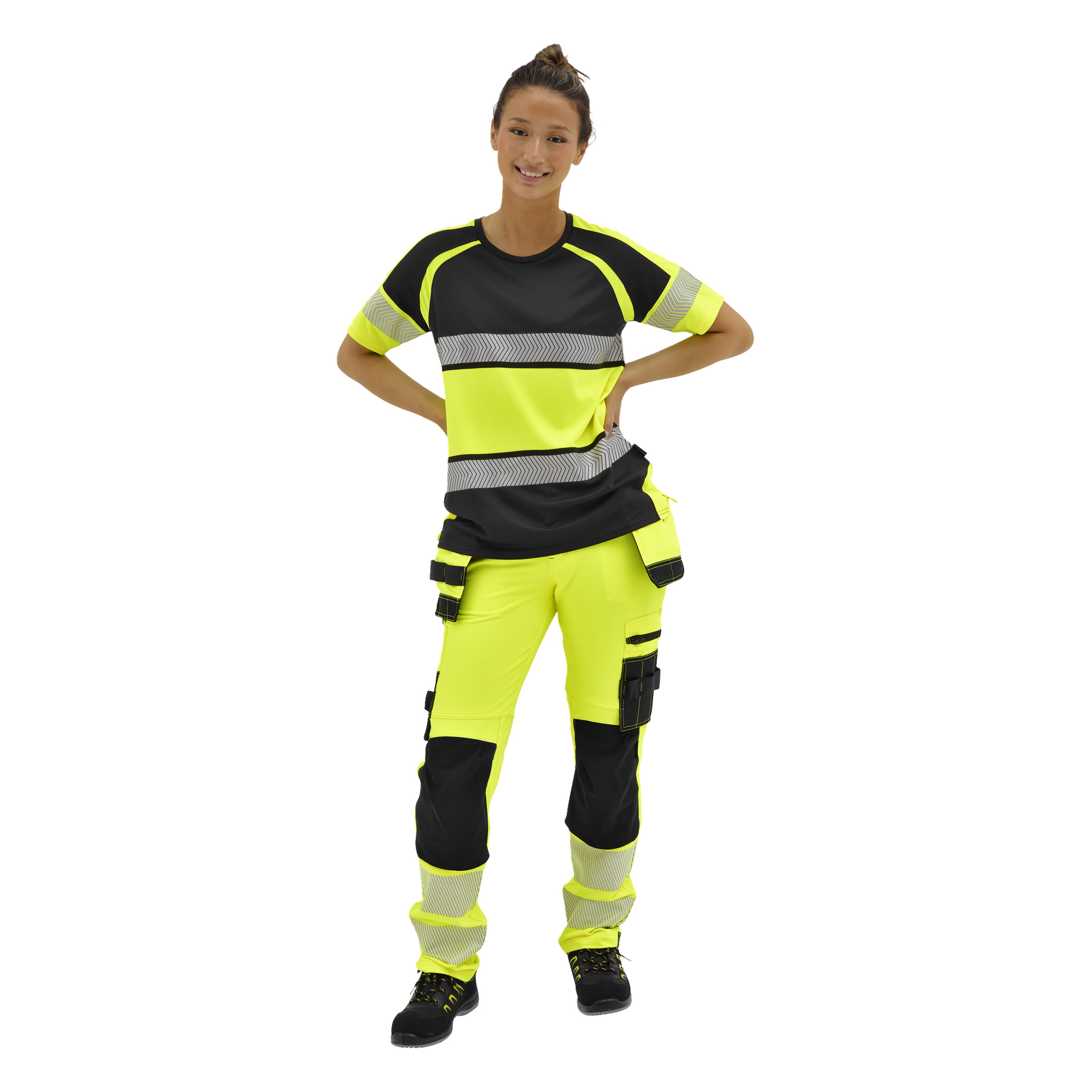 Leende person med handen på höften modellerar Bluewear Pro Workwear Stella-byxor i neongult med svarta fickor och reflekterande ränder.