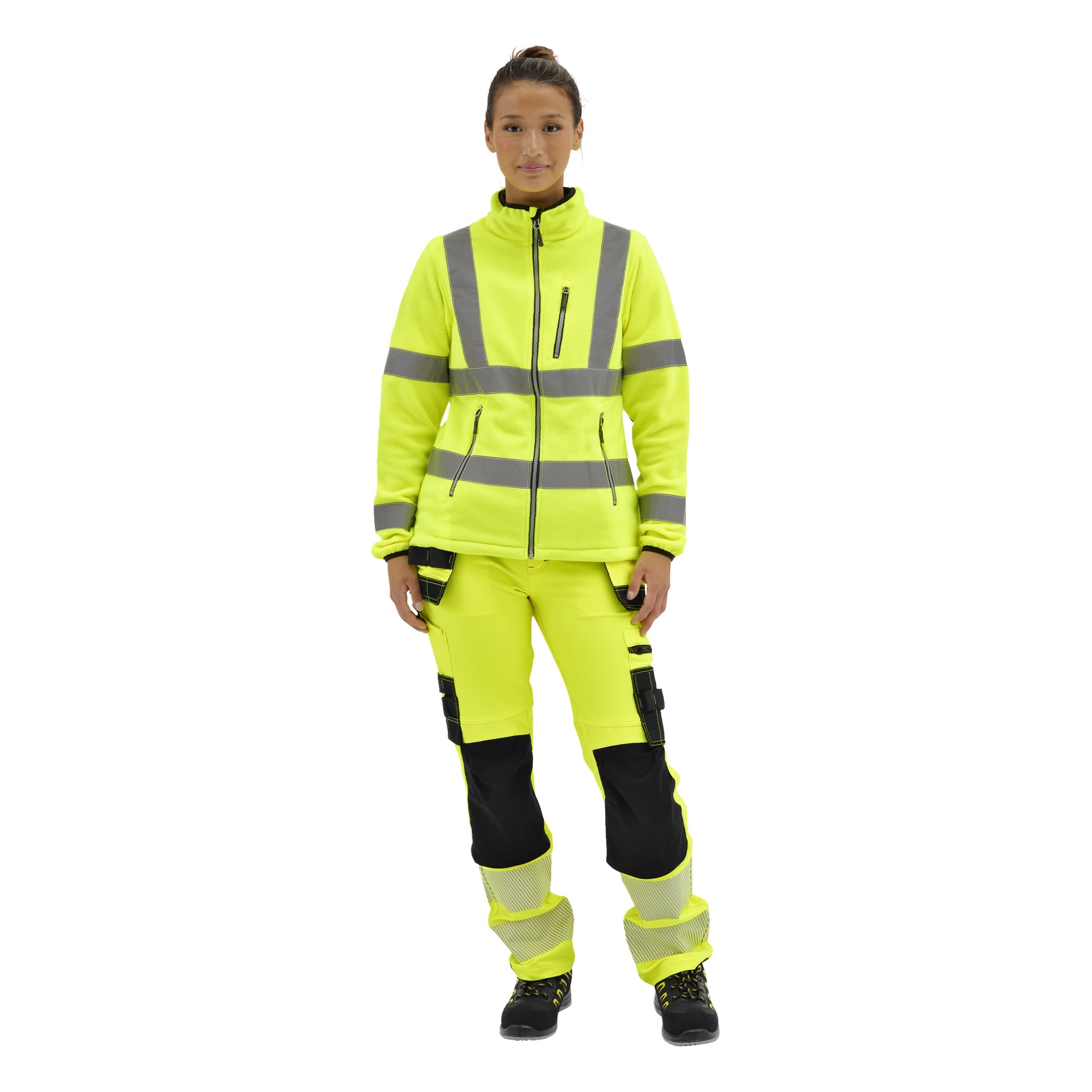 En kvinna står vänd framåt i en gul Bluewear Dames högsynlig fleecejacka med reflekterande ränder, matchande byxor och svarta arbetsskor.