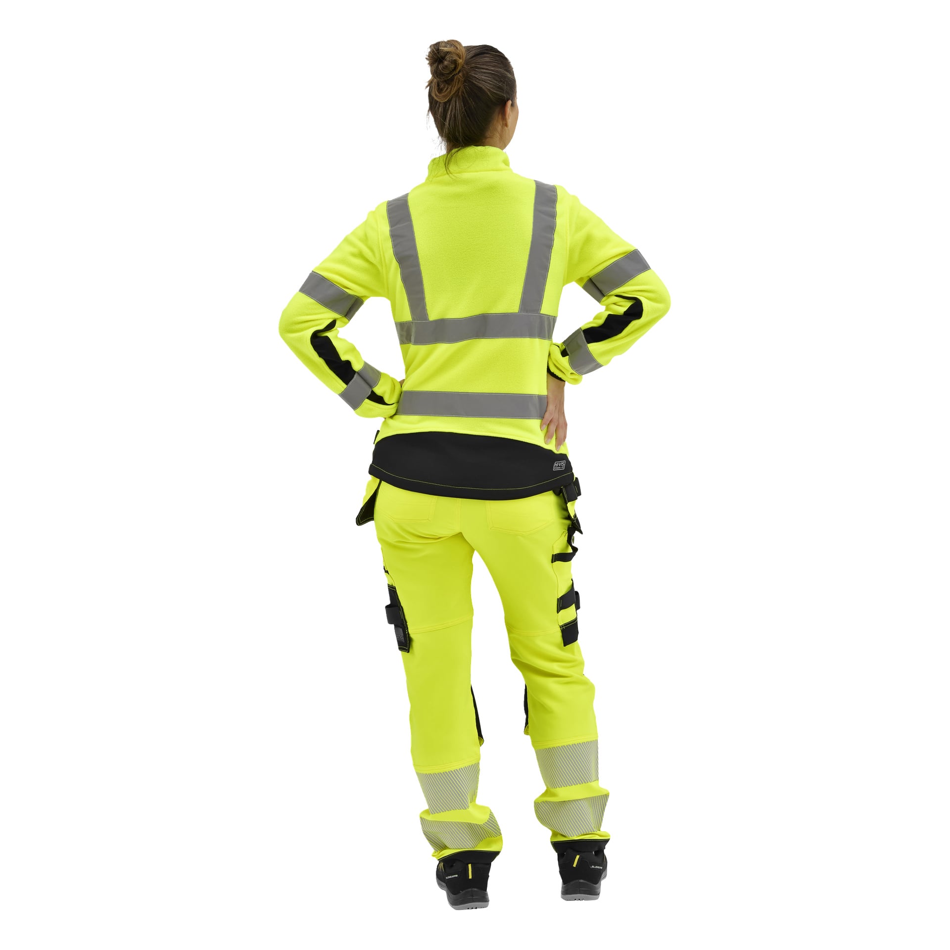 Person sedd bakifrån i en gul hög-vis Bluewear Dames fleecejacka med reflekterande remsor, håret uppsatt, bärande svarta skor.