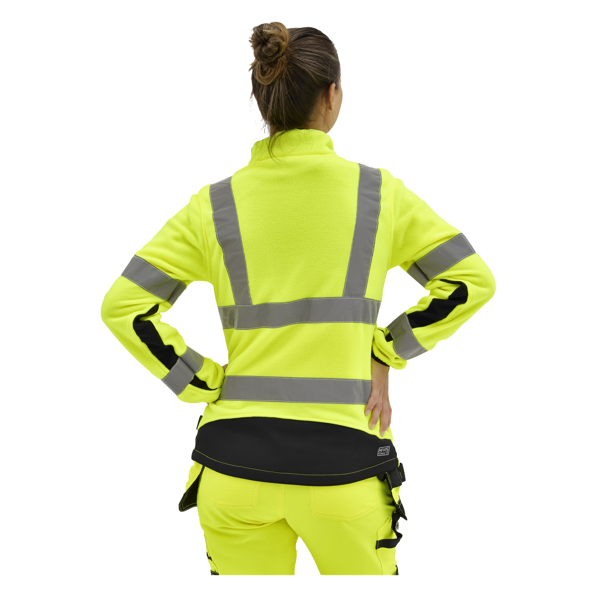 En kvinna står med händerna på höfterna, ryggen mot kameran, i en klargul Bluewear hög-vis-fleecejacka med grå ränder och svarta detaljer.
