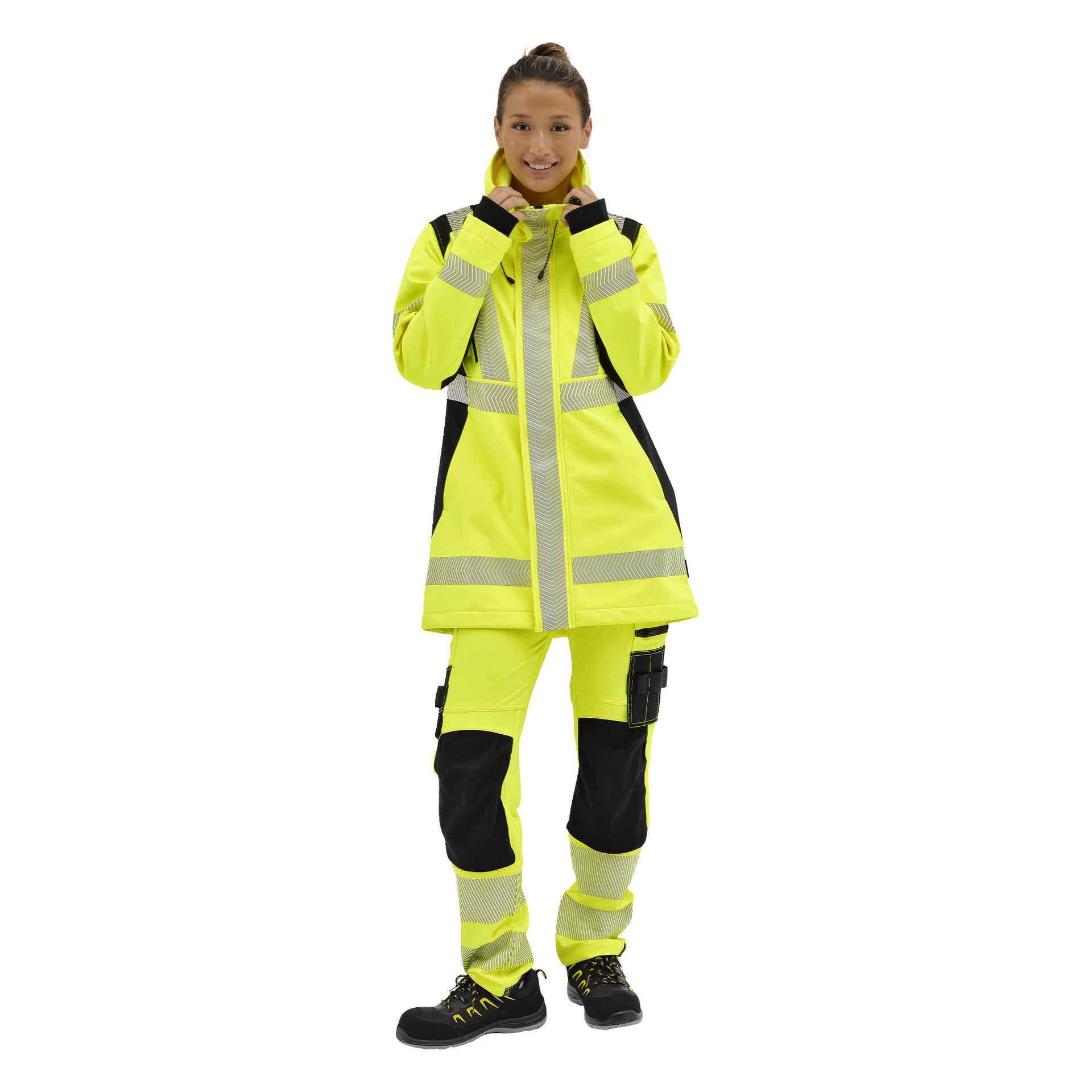 En person klädd i en gul och svart Bluewear Hi-Vis softshelljacka med reflekterande remsor, matchande byxor och svarta skor.