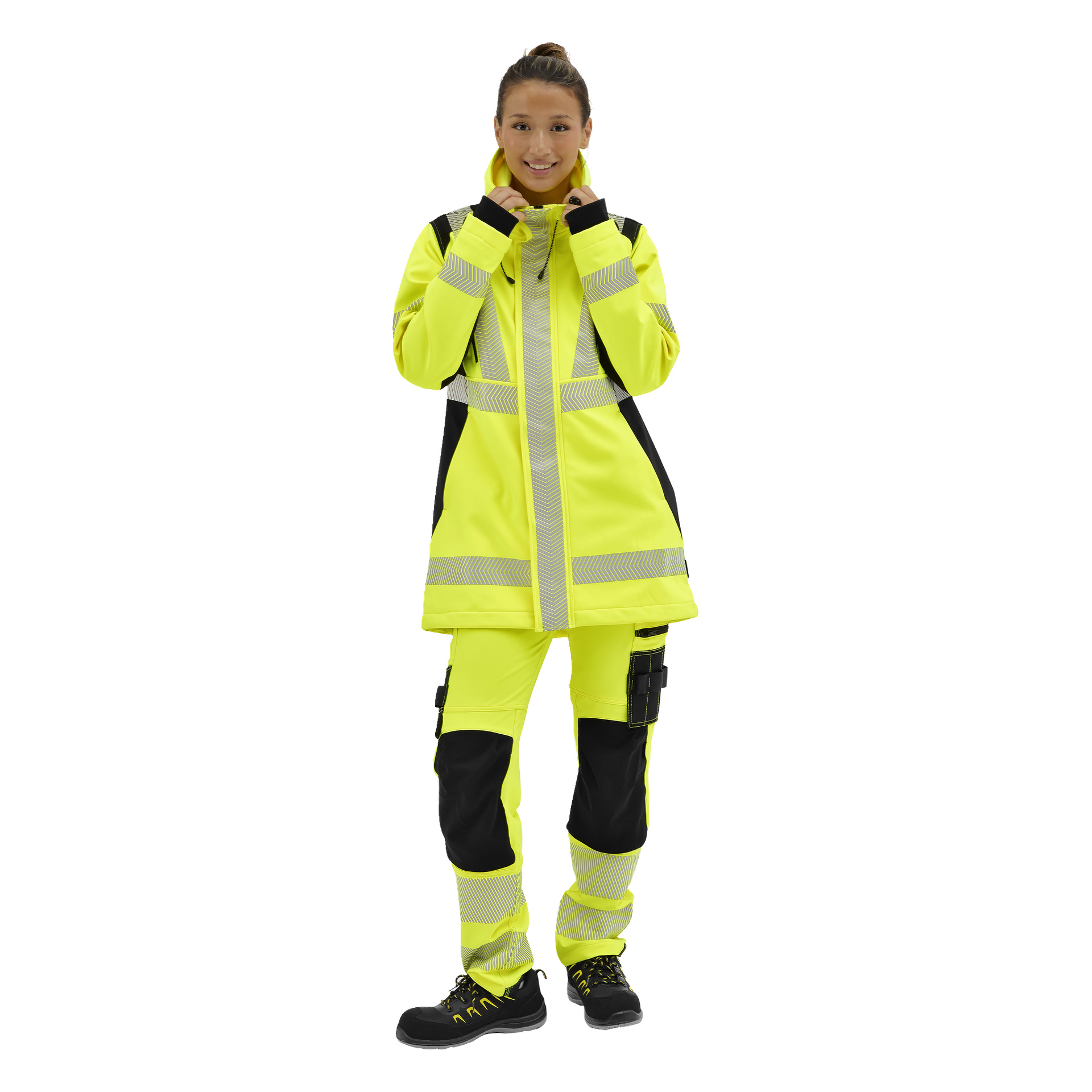 En leende person bär en Bluewear Hi-Vis Merrit softshelljacka och byxor med reflekterande ränder, svarta detaljer och gula snörskor.