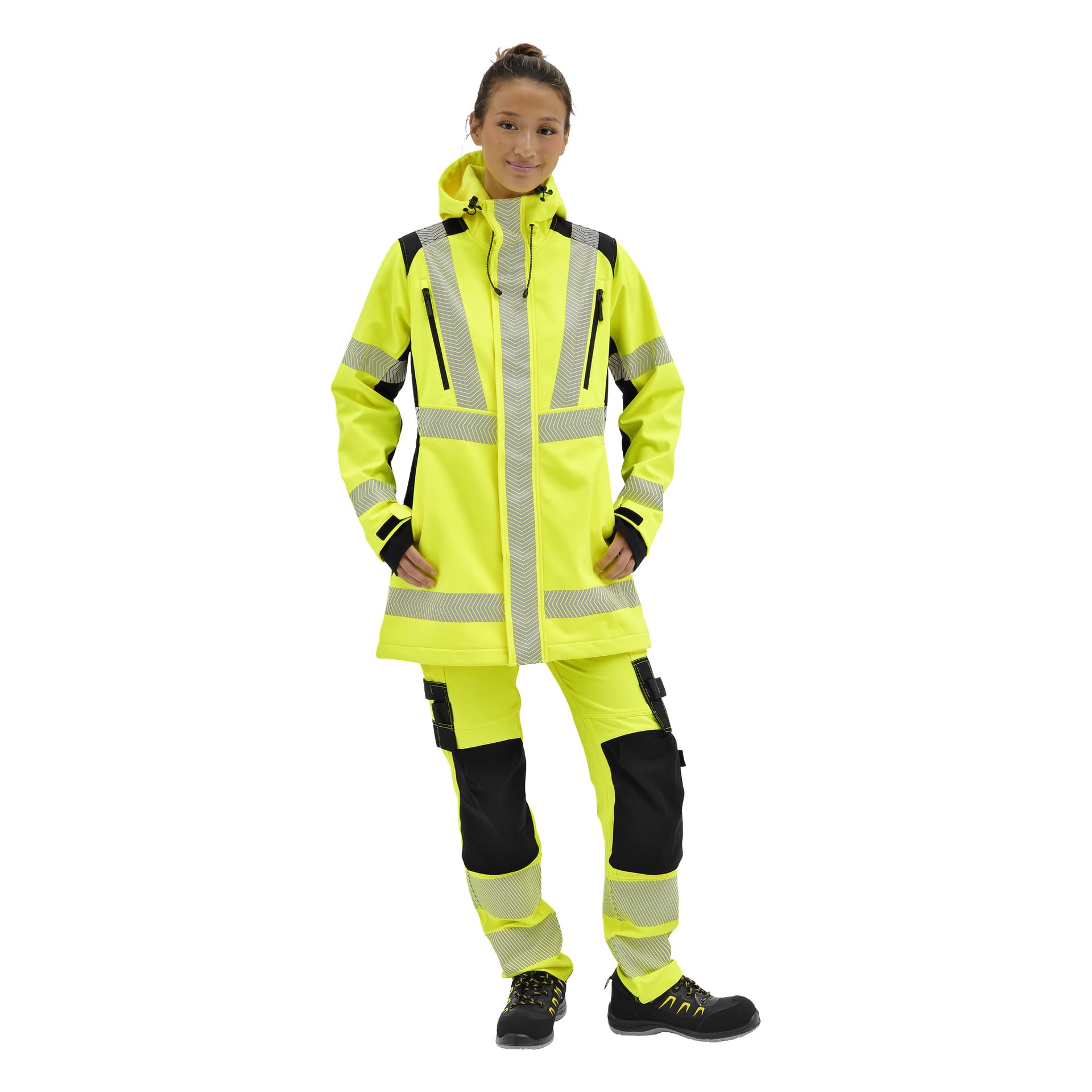 Någon modellerar Bluewear Hi-Vis gula softshelljackan Merrit med reflekterande ränder, svarta detaljer, matchande byxor och arbetsskor.