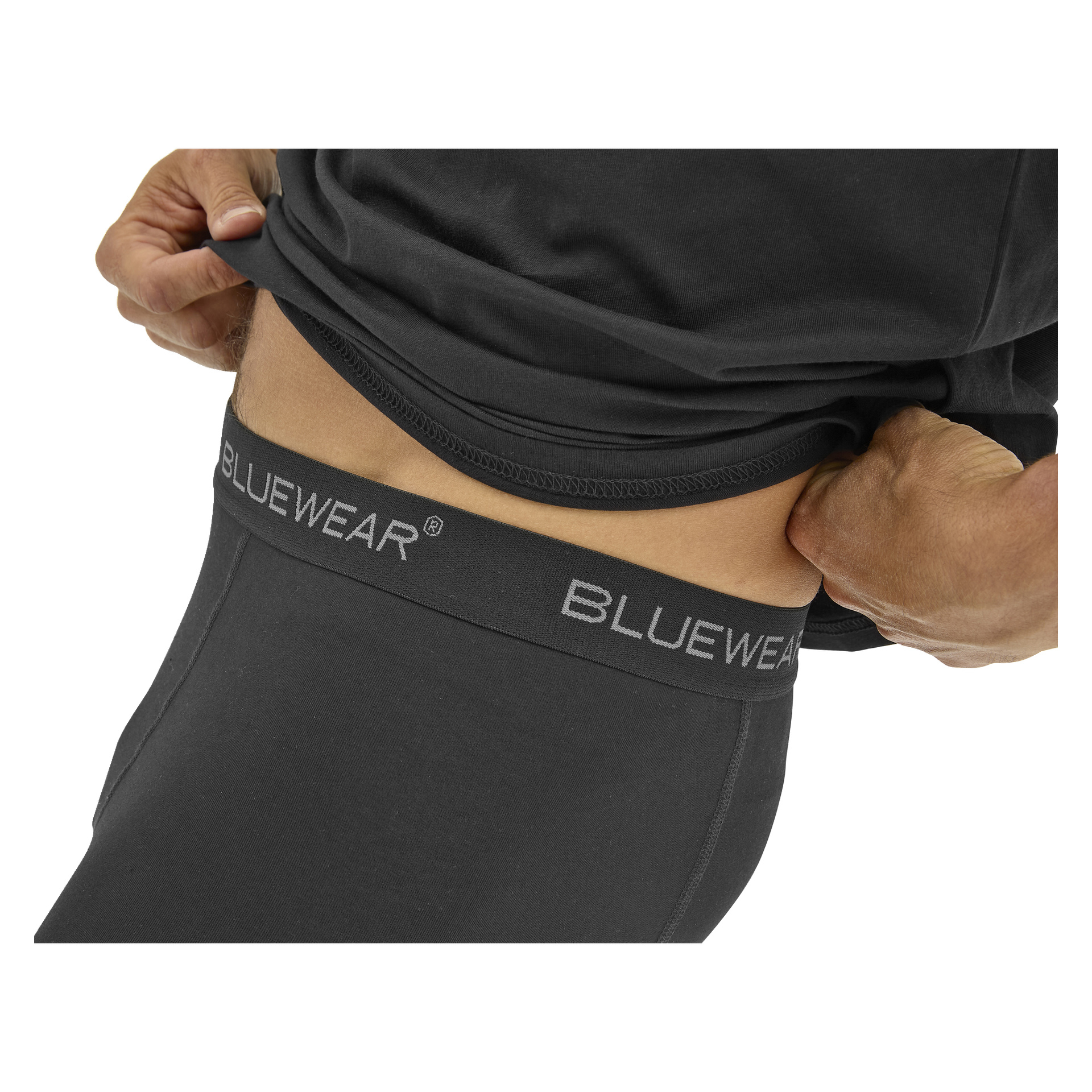 En person lyfter en svart skjorta och blottar midjebandet på svarta Bluewear-byxor eller underkläder.