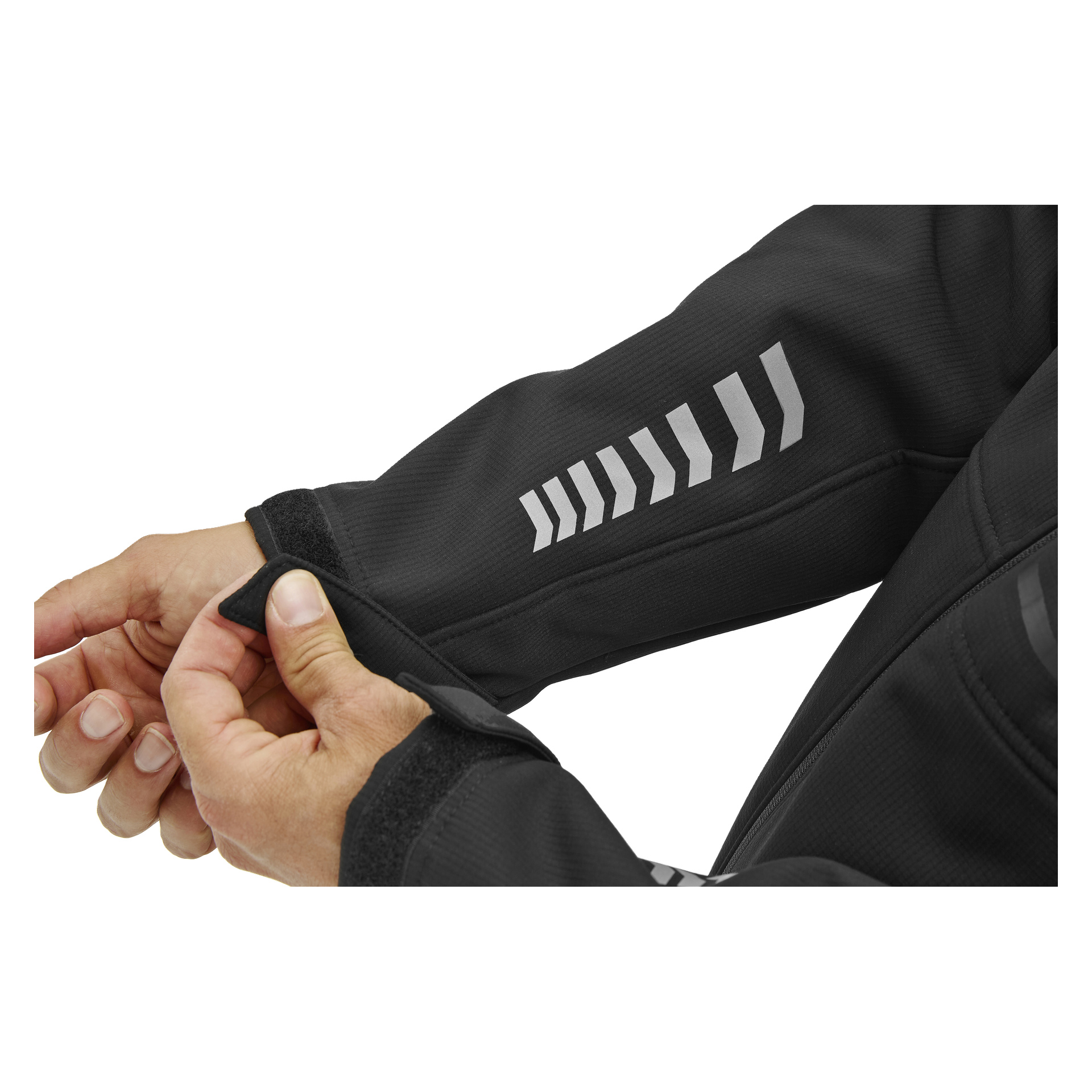Någon fäster kardborrebandsmanschetten på en Bluewear Gustaf herrjacka i svart softshell-jacka med reflekterande chevron-ränder på underarmen.