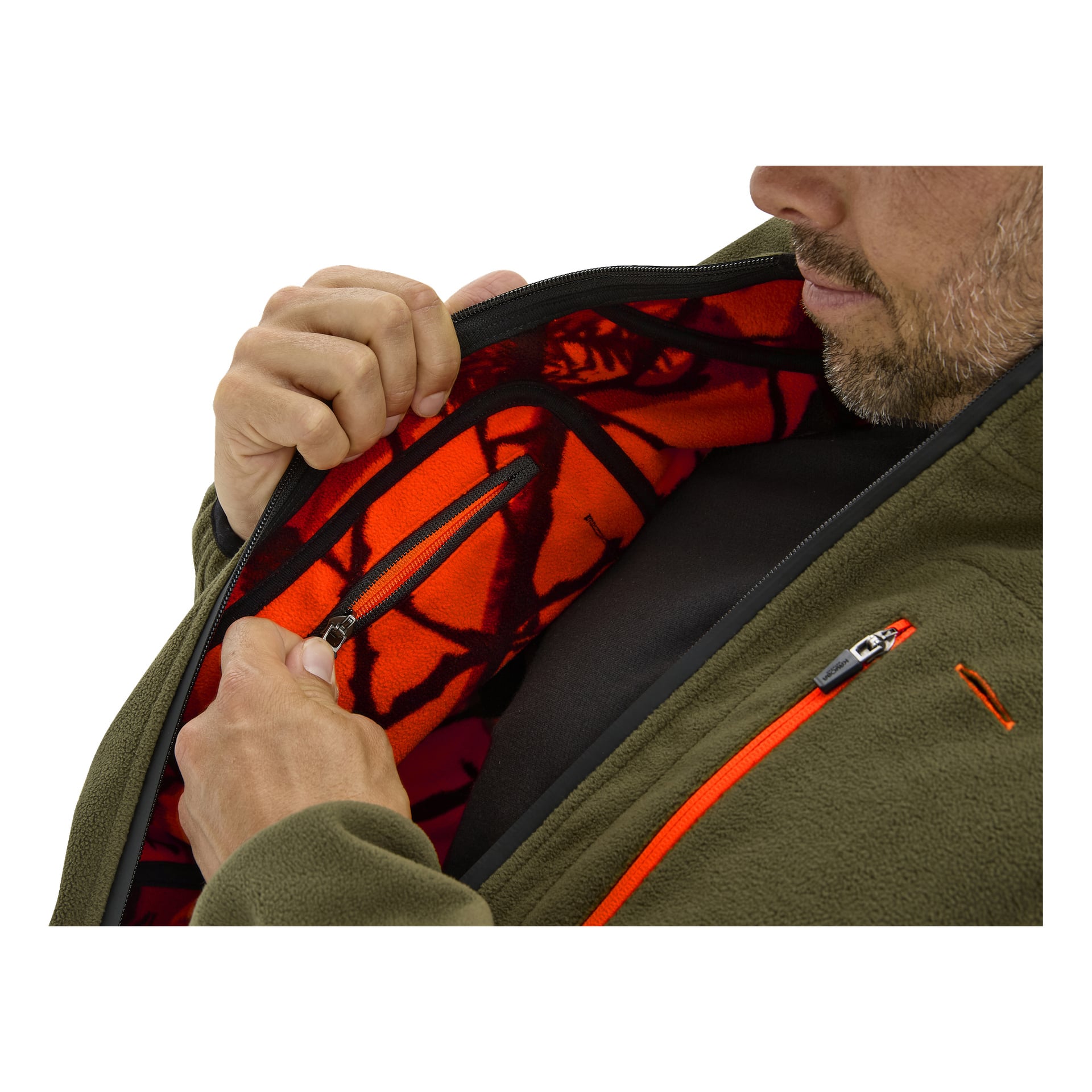 Ein Mann öffnet eine olivgrüne Kayoba-Outdoor-Jacke, die rot-schwarzes Tarnfleecefutter, eine Innentasche mit Reißverschluss und einen orangefarbenen Brustreißverschluss zeigt.