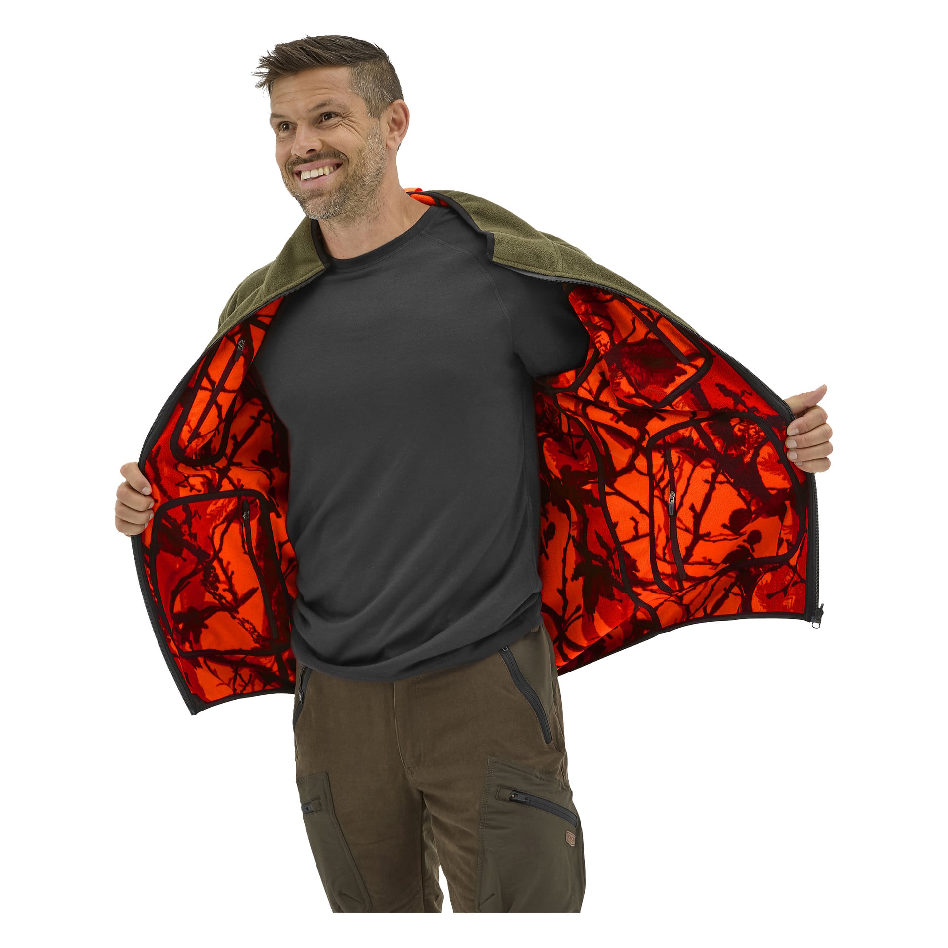 Der lächelnde Mann hält eine Kayoba Outdoor Cannock-Jacke offen und enthüllt ein leuchtend orange-schwarzes Tarnfutter; Trägt ein dunkles T-Shirt und braune Hosen.