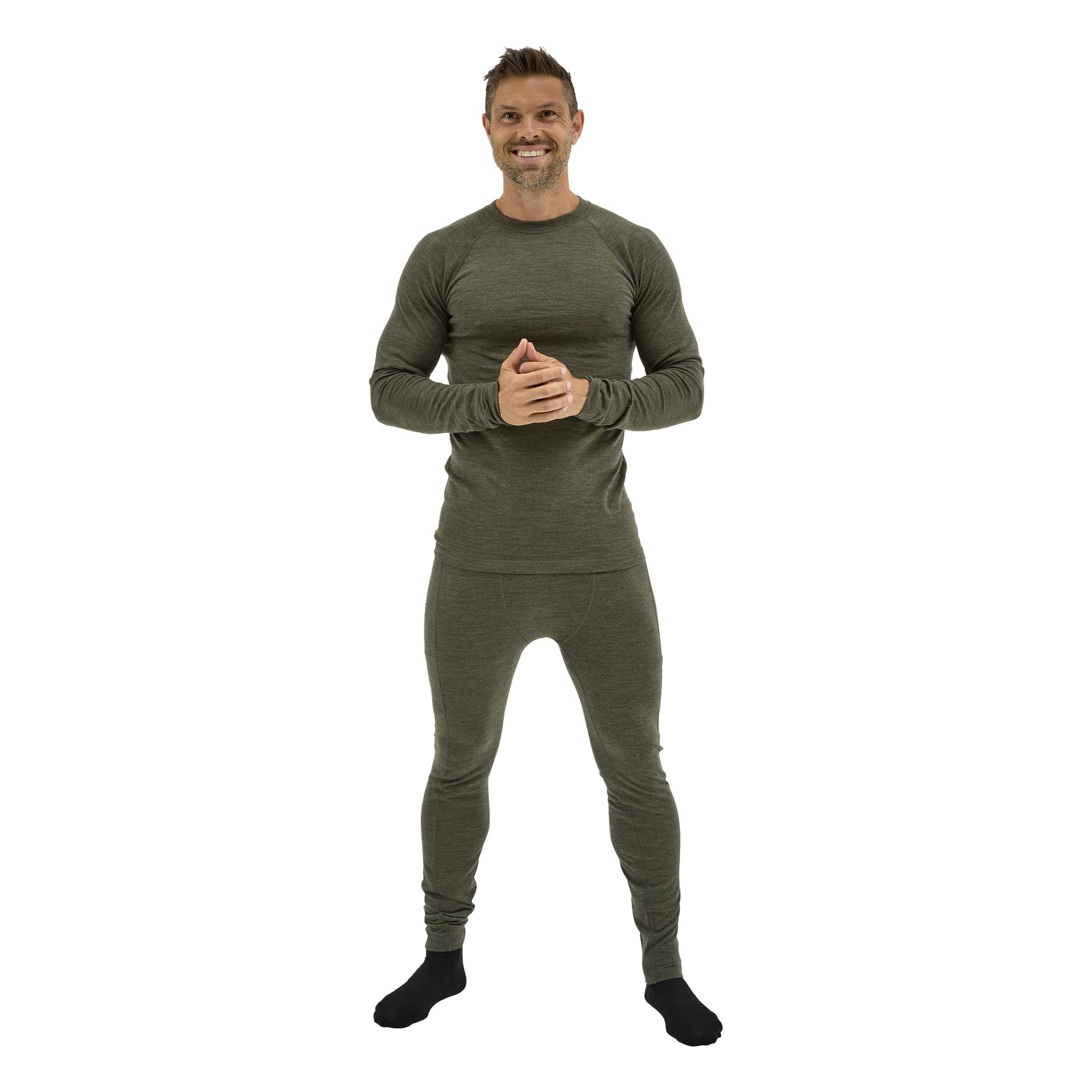 En man ler framåt, händerna knäppta, klädd i olivgrönt Kayoba Outdoor Merino ullbaslager och svarta strumpor.