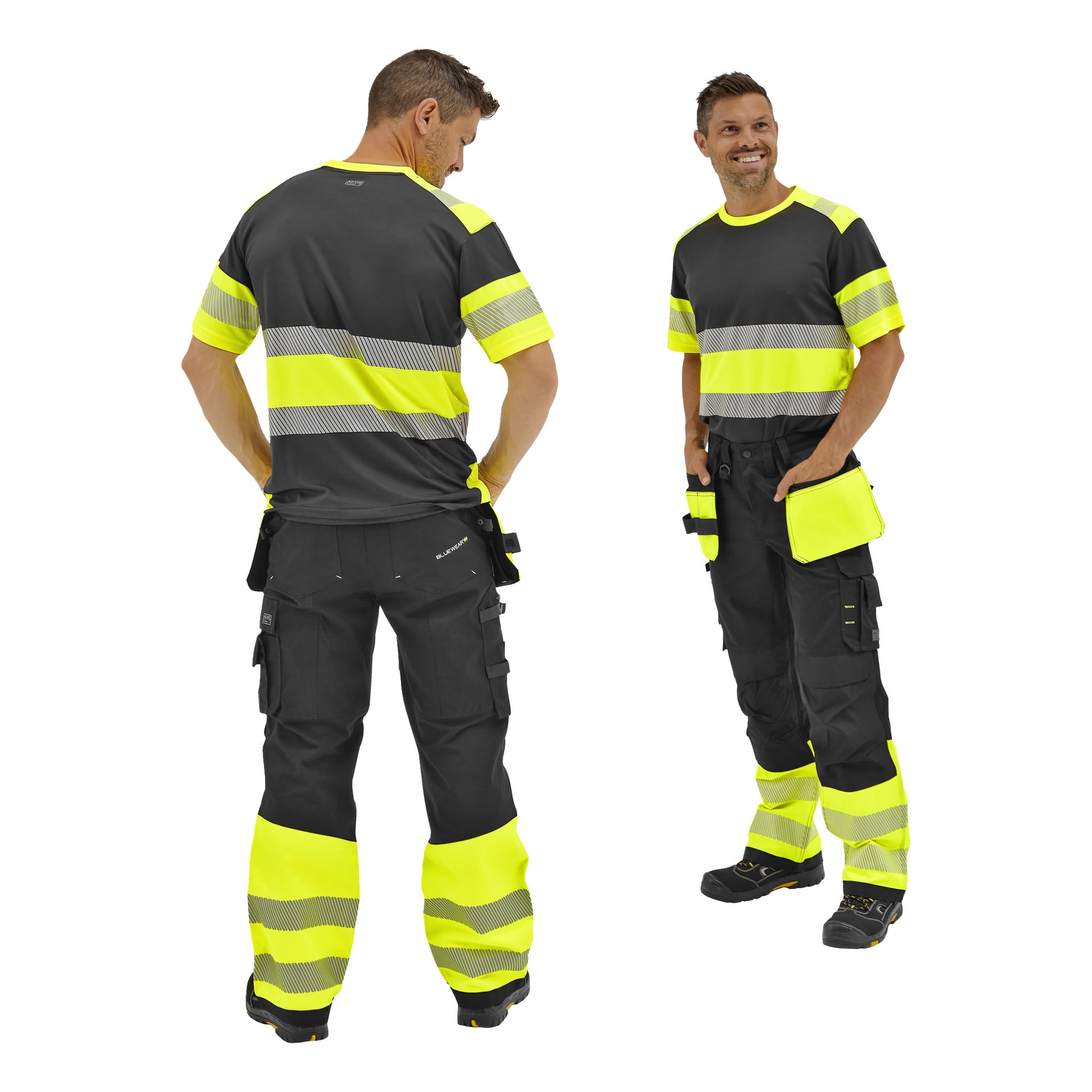 Två män i Bluewear Rex hög-vis-byxor och svarta/gula reflekterande skjortor; Den ena vänder sig framåt och ler, den andra visar ryggen. Båda bär svarta arbetsstövlar.