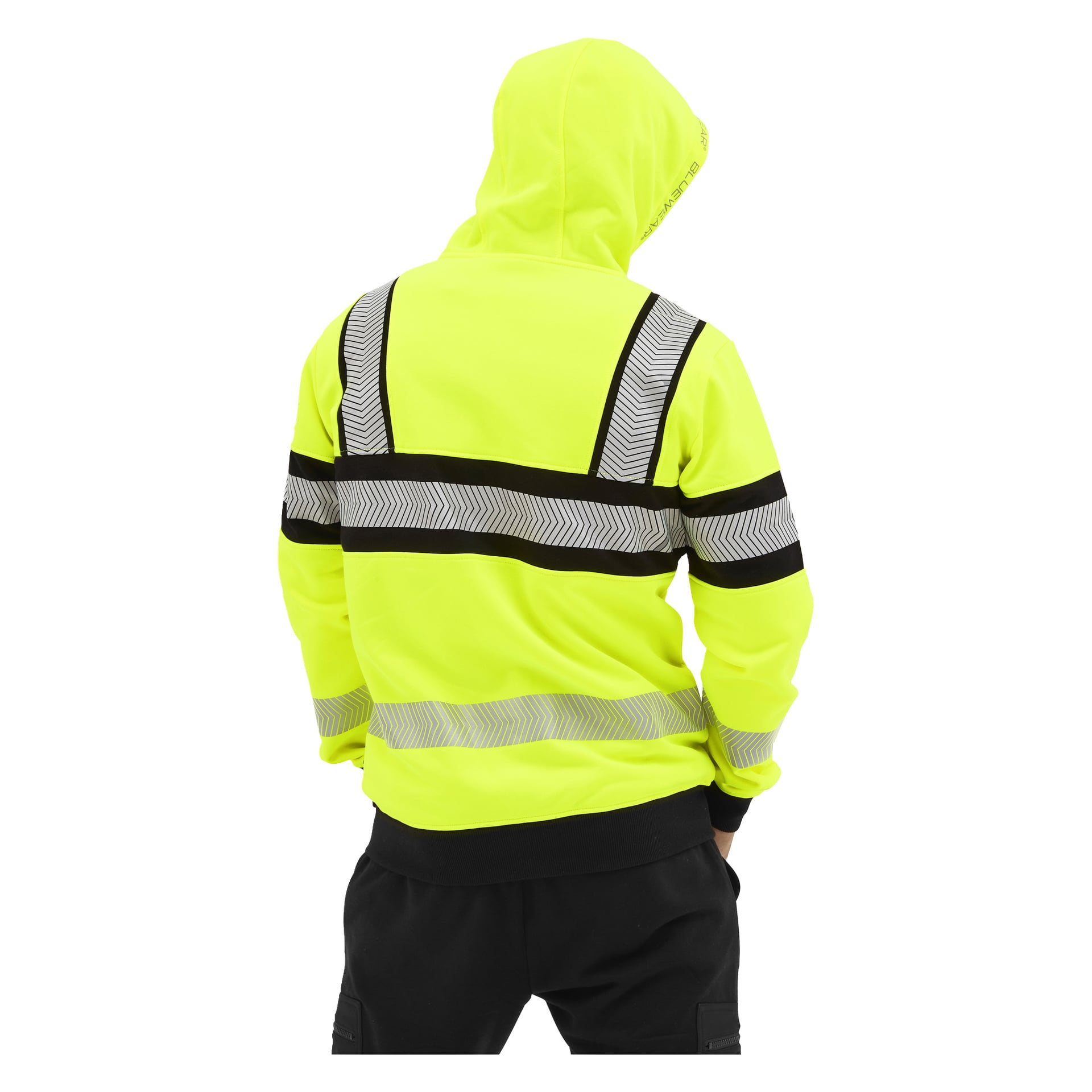 Personen i en Bluewear Hi-vis Chambley-hoodie med gult tyg, chevron-ränder och svarta detaljer står med händerna i fickorna, ryggen mot kameran.