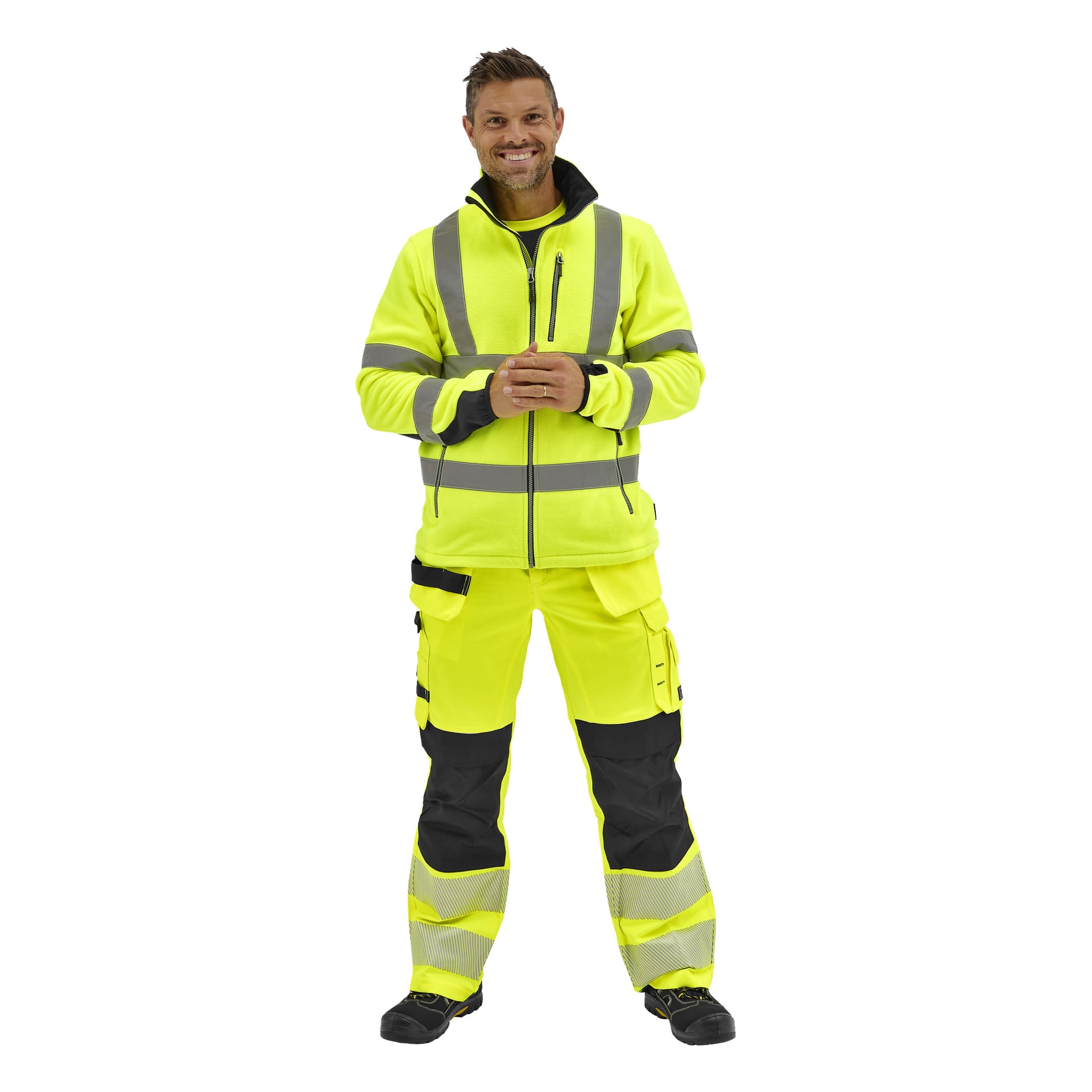 En leende man står framåtvänd i en Bluewear Hi-Vis fleecejacka med reflekterande remsor, matchande arbetsbyxor och skor.
