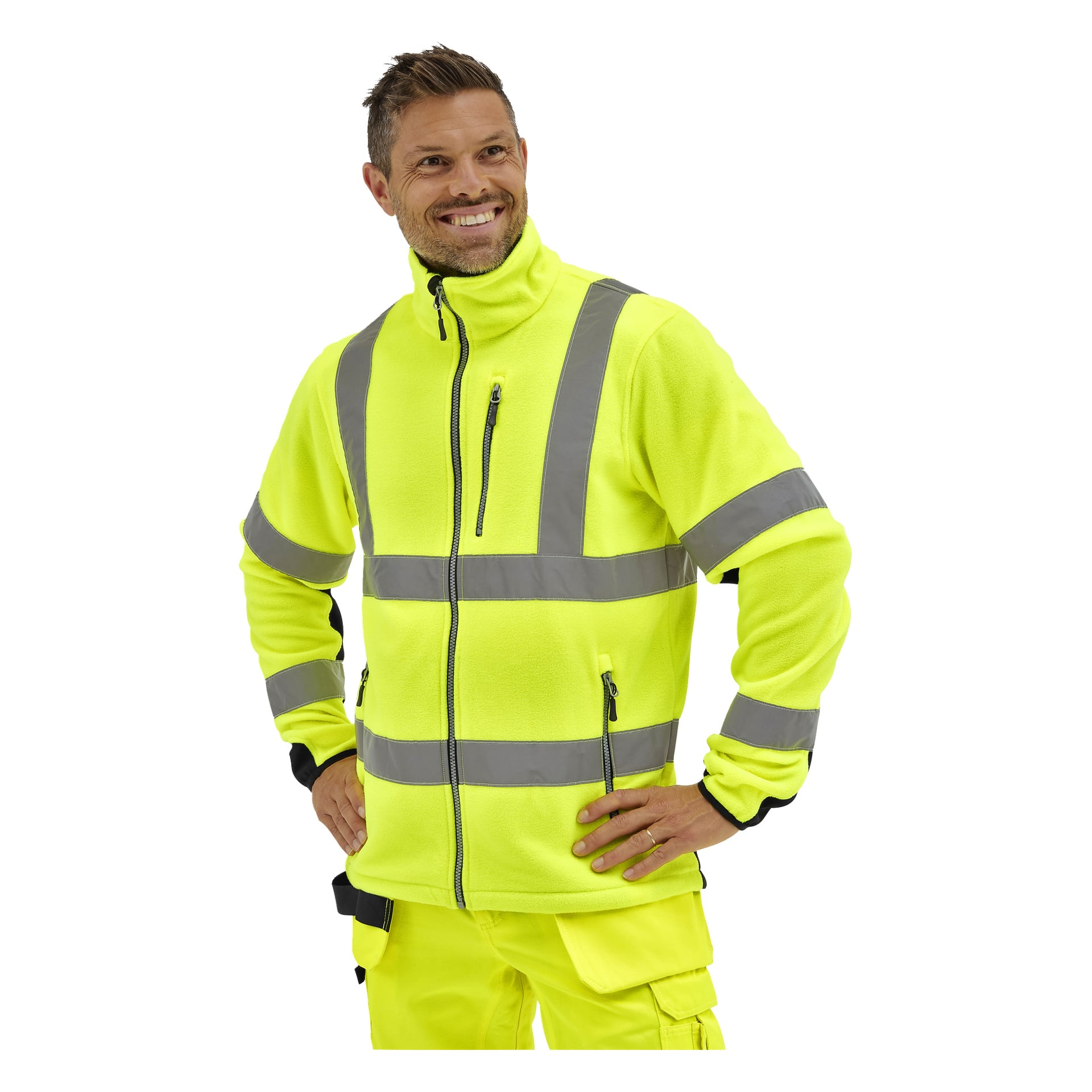 En man i en Bluewear Hi-Vis fleecejacka med reflekterande ränder ler, händerna på höfterna, och kastar en blick åt sidan.
