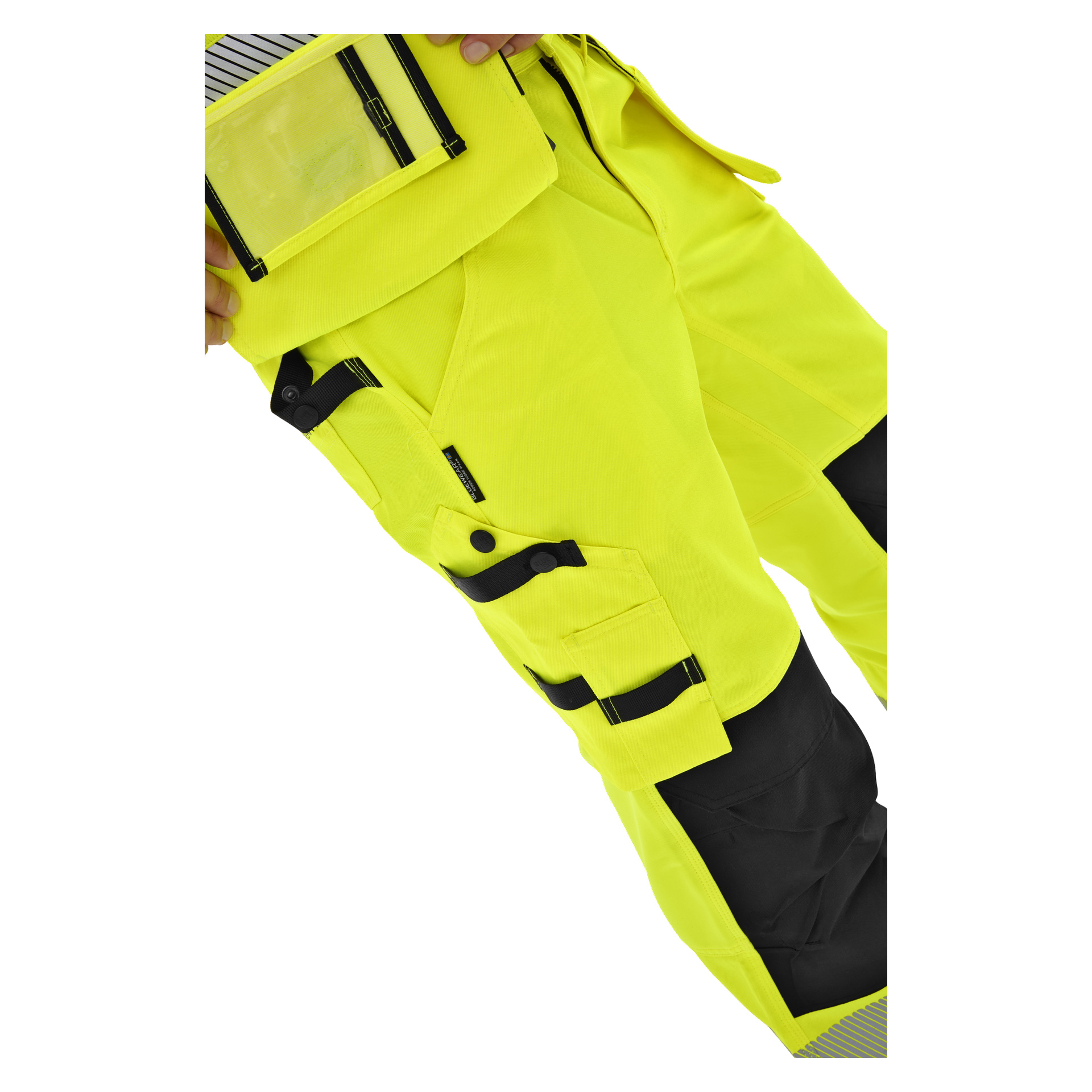 Midjevy och nedåt av en person i neongula Bluewear Rex högvarselbyxor med svarta detaljer, flera fickor och en genomskinlig ficka.