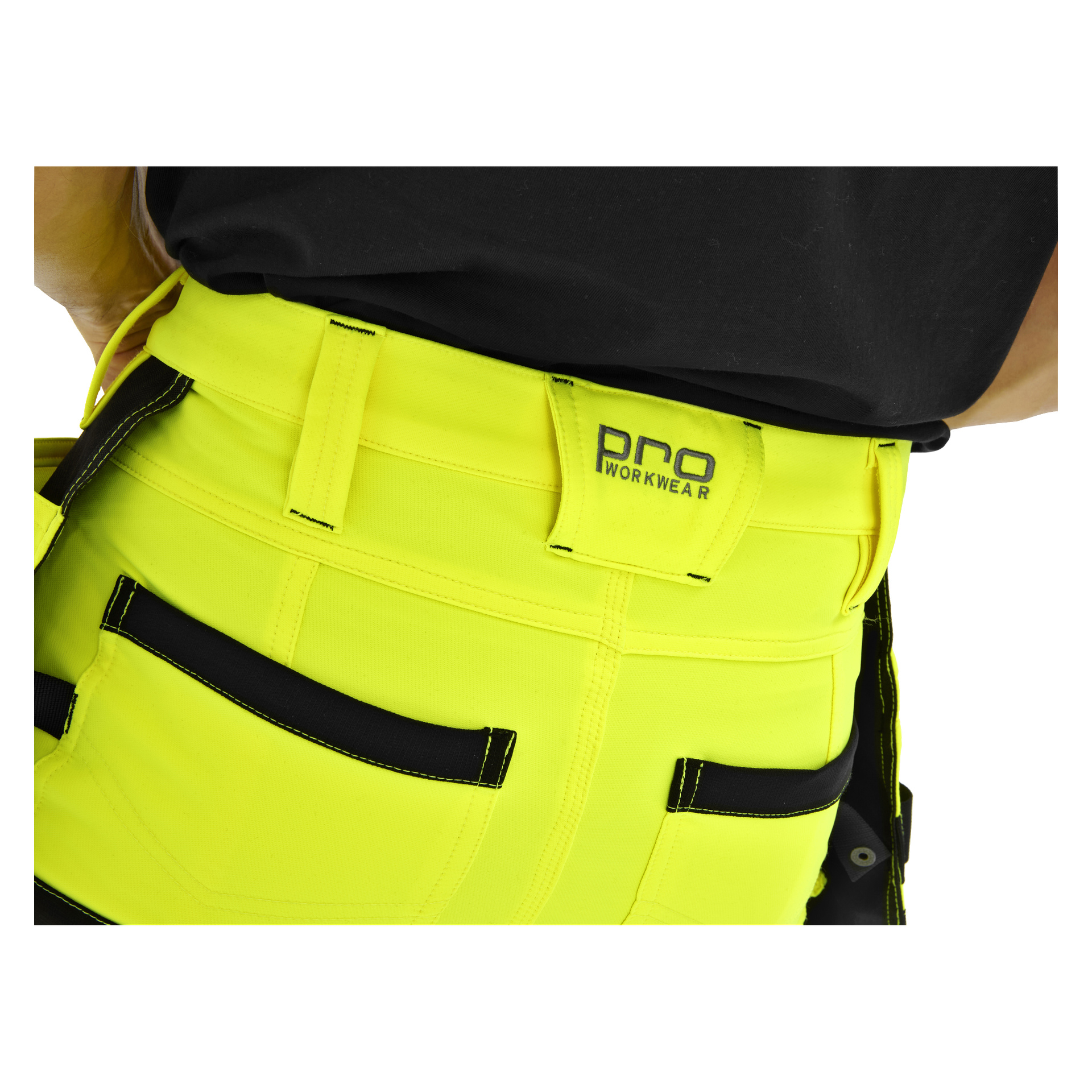 Närbild på en person i klargula Bluewear Pro Workwear Steve-byxor med svart kant, bältesöglor, fickor och en PRO WORKWEAR-etikett.