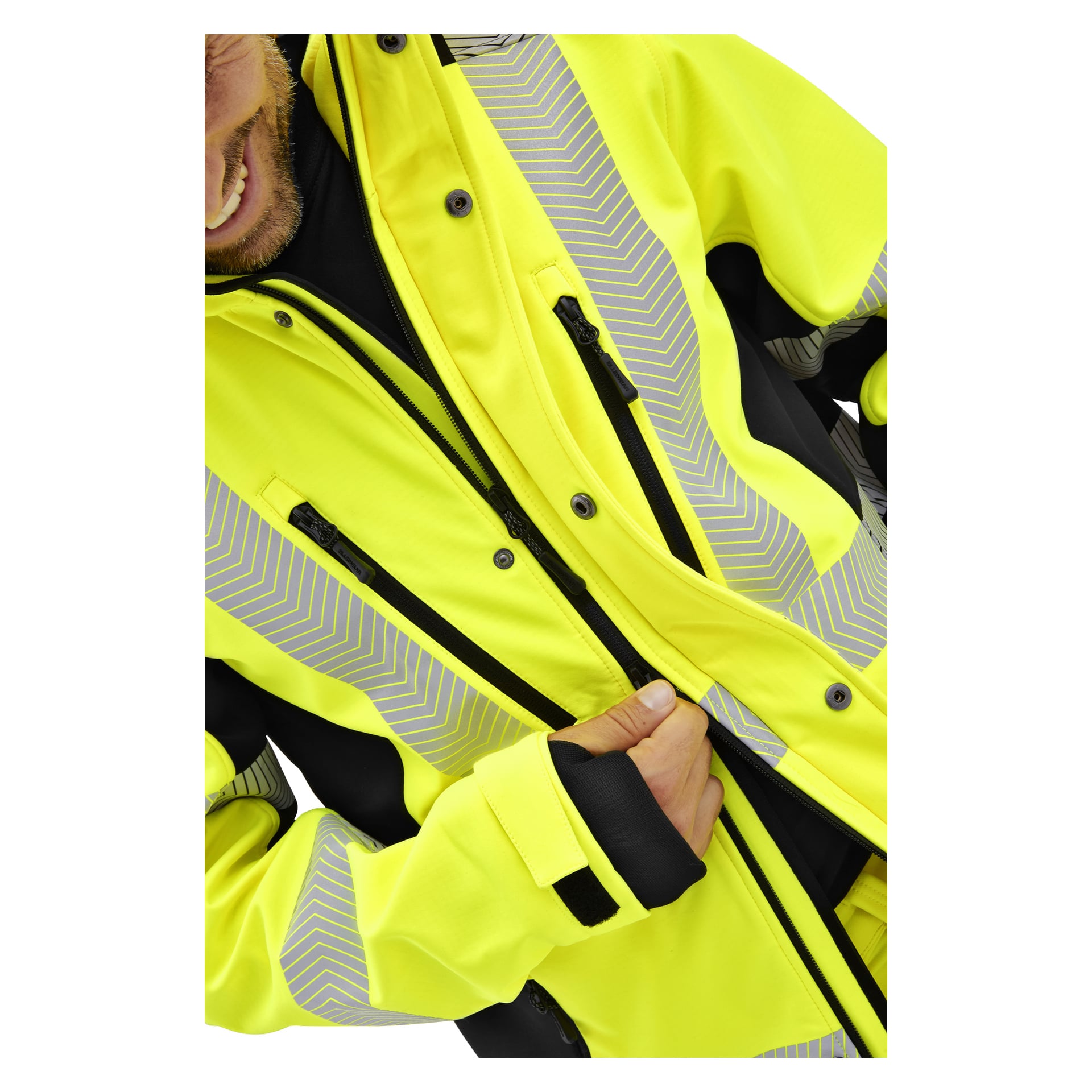 Eine Person zieht eine Bluewear Hi-Vis Kingston-Jacke mit gelbem Stoff und reflektierenden Streifen zu, sodass nur das untere Gesicht und die Hand sichtbar sind.