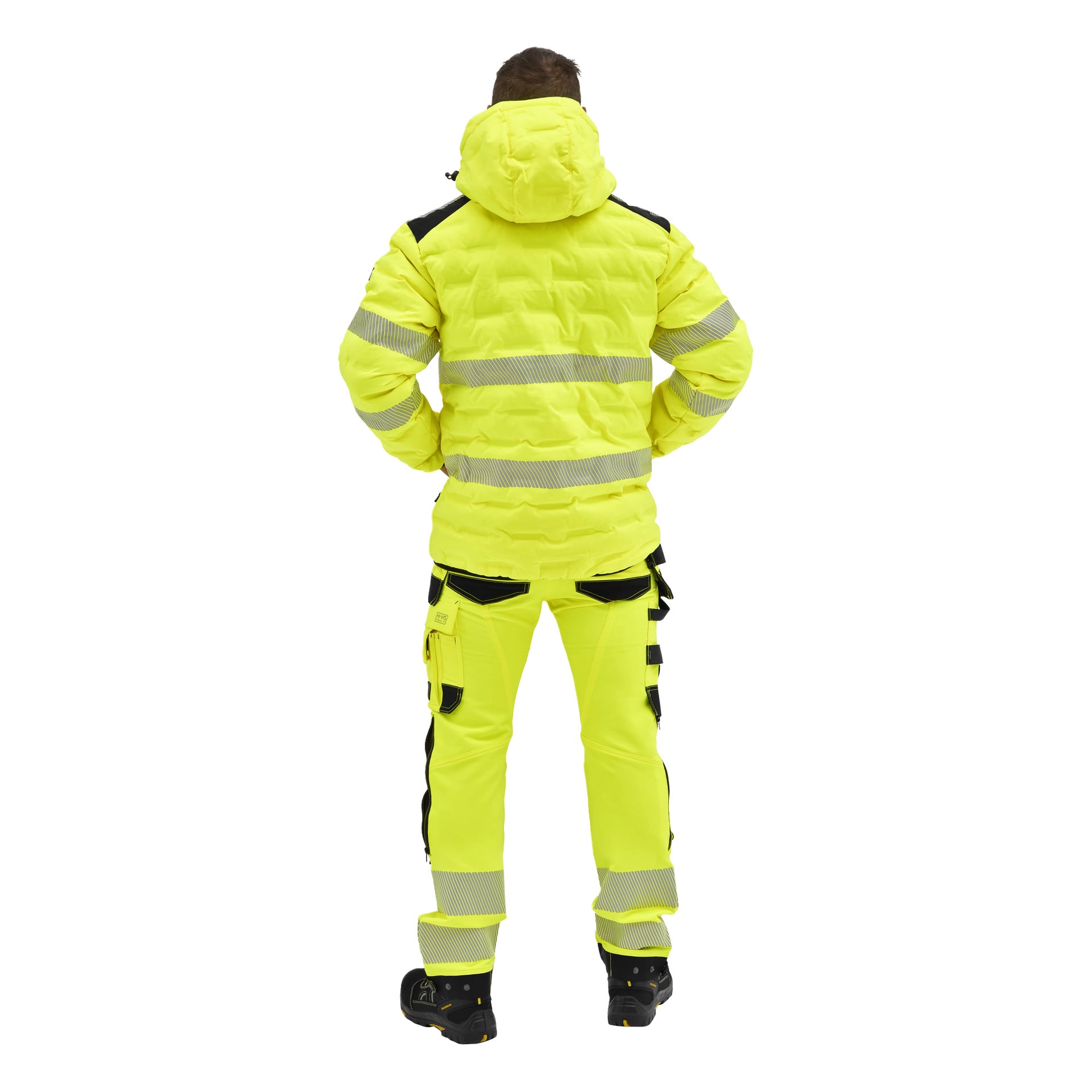 En person vänder sig bort, klädd i en Bluewear Pro hi-vis vadderad jacka och byxor med reflekterande band, svarta detaljer och arbetskängor.