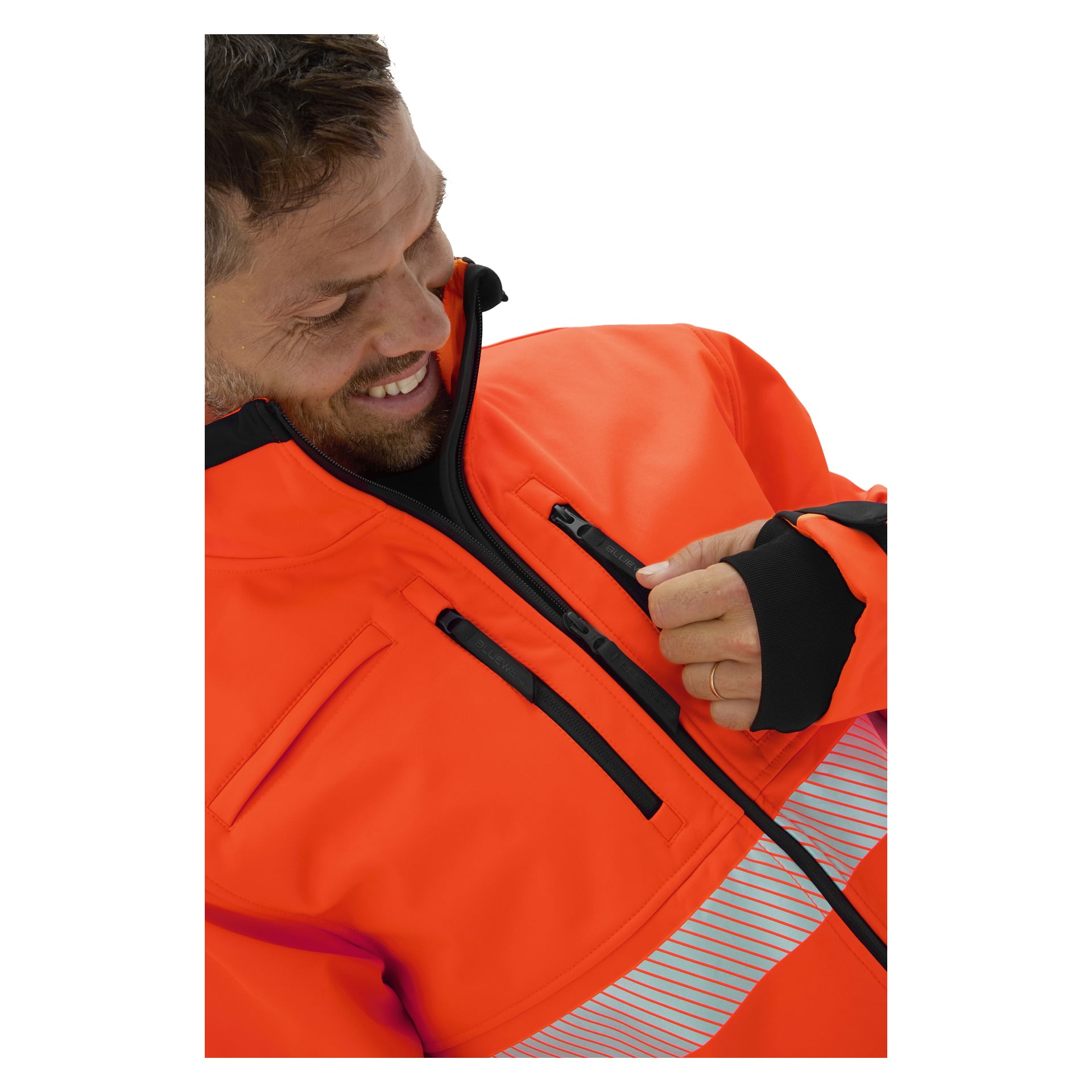 Man drar ner dragkedjan på bröstfickan på en Bluewear Hi-Vis softshelljacka i Toronto med svarta dragkedjor, reflekterande ränder och tumhål.