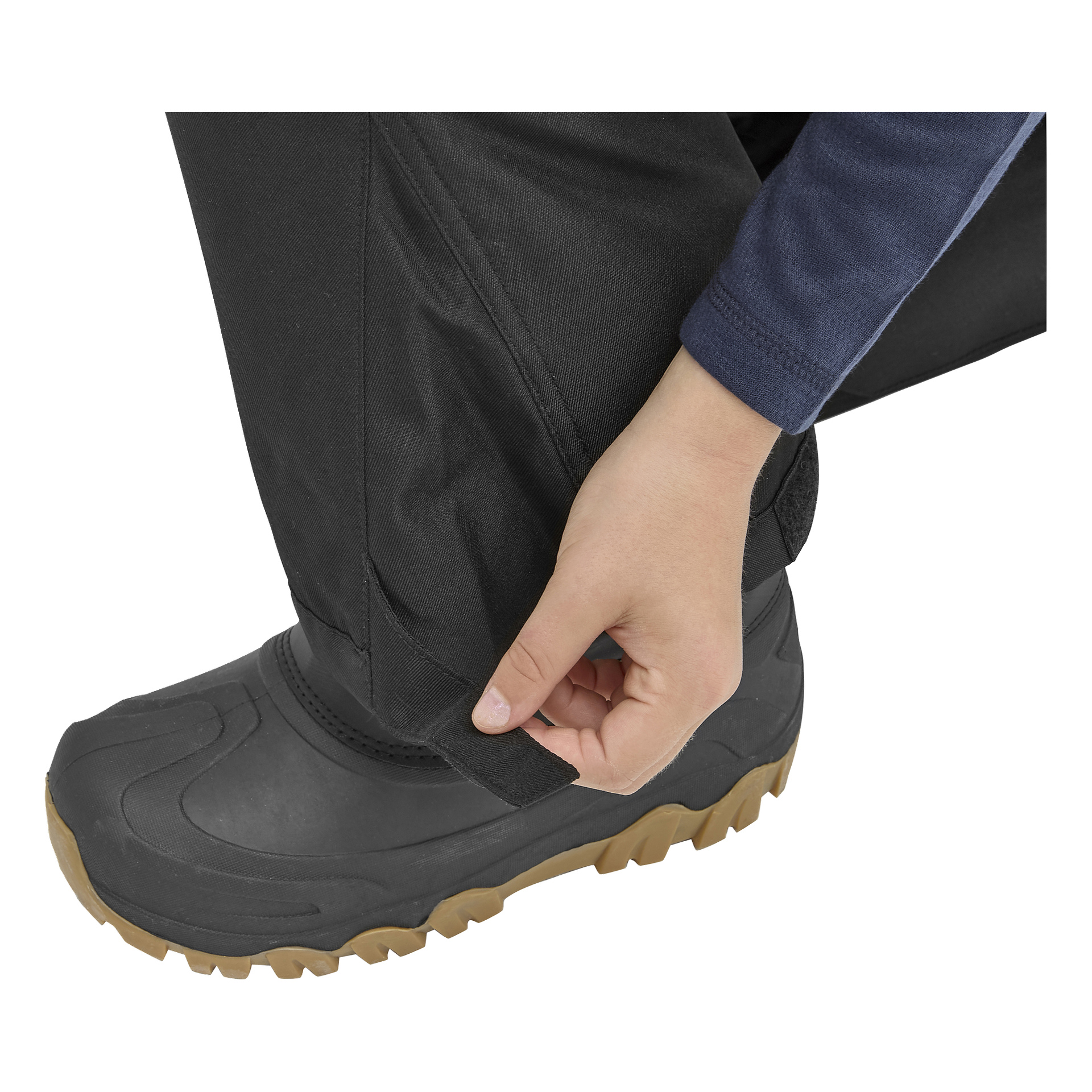 En person i Kaloba Outdoor Children's termobyxor drar åt en rem vid vristen över en svart och beige vandringskänga.