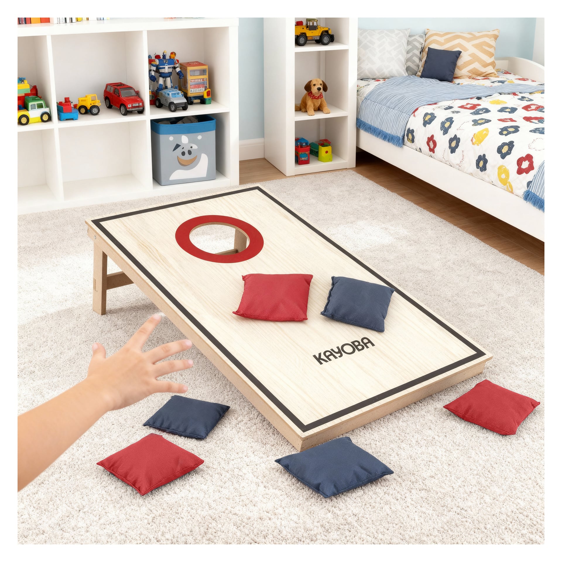 En barnhand kastar en blå bönpåse mot ett cornhole-bräde i trä med en röd ring på hålet, flera röda och blå bönpåsar på och runt brädet, i ett sovrum med heltäckningsmatta, leksaker och en säng i bakgrunden. Bilden är framställd med hjälp av ai. 