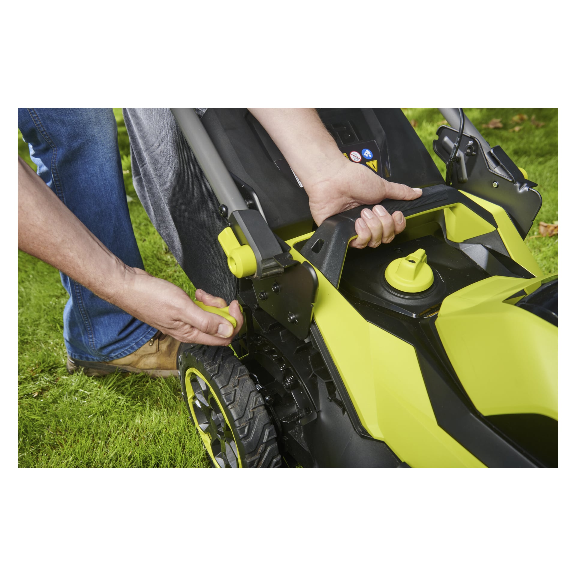 En person på gräs justerar höjden på en Ryobi Max Power-batterigräsklippare genom att använda spaken och hålla i handtaget.