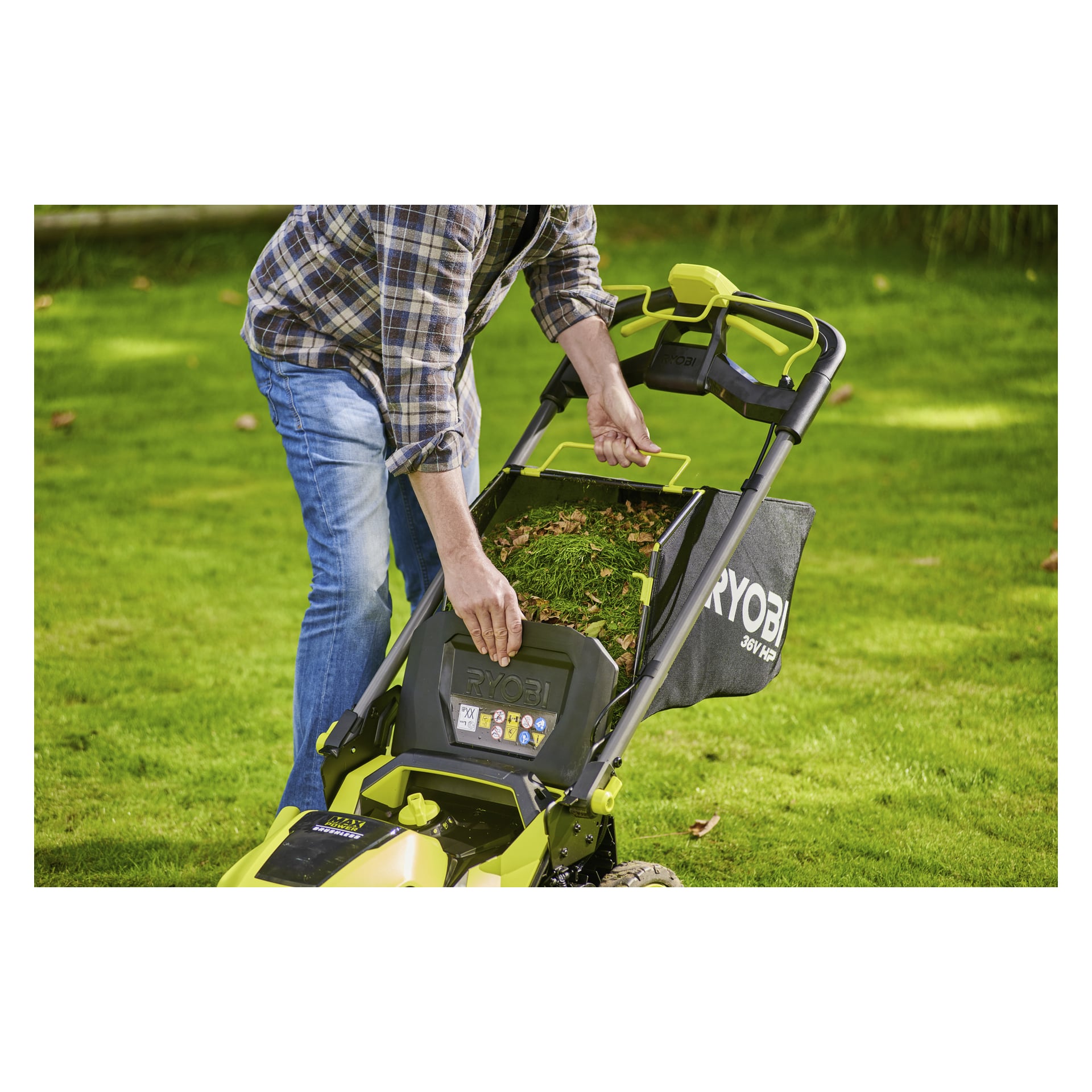 Iklädd jeans och rutig skjorta tömmer man gräsklipp från en Ryobi-batterigräsklippare på en grön gräsmatta.