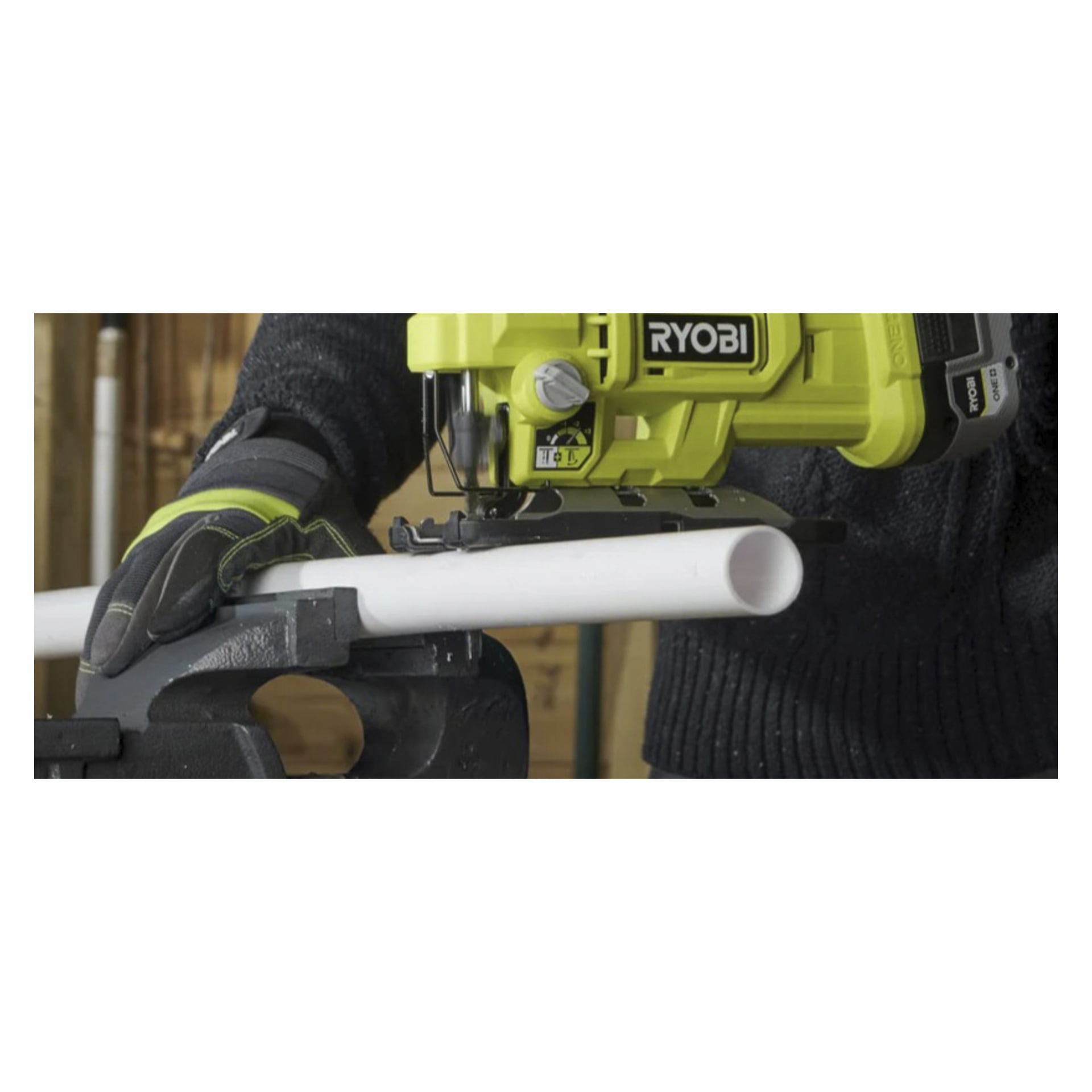Handskbeklädda händer använder en RYOBI-sticksåg för att skära ett vitt PVC-rör som sitter stadigt i ett metallskruvstäd.