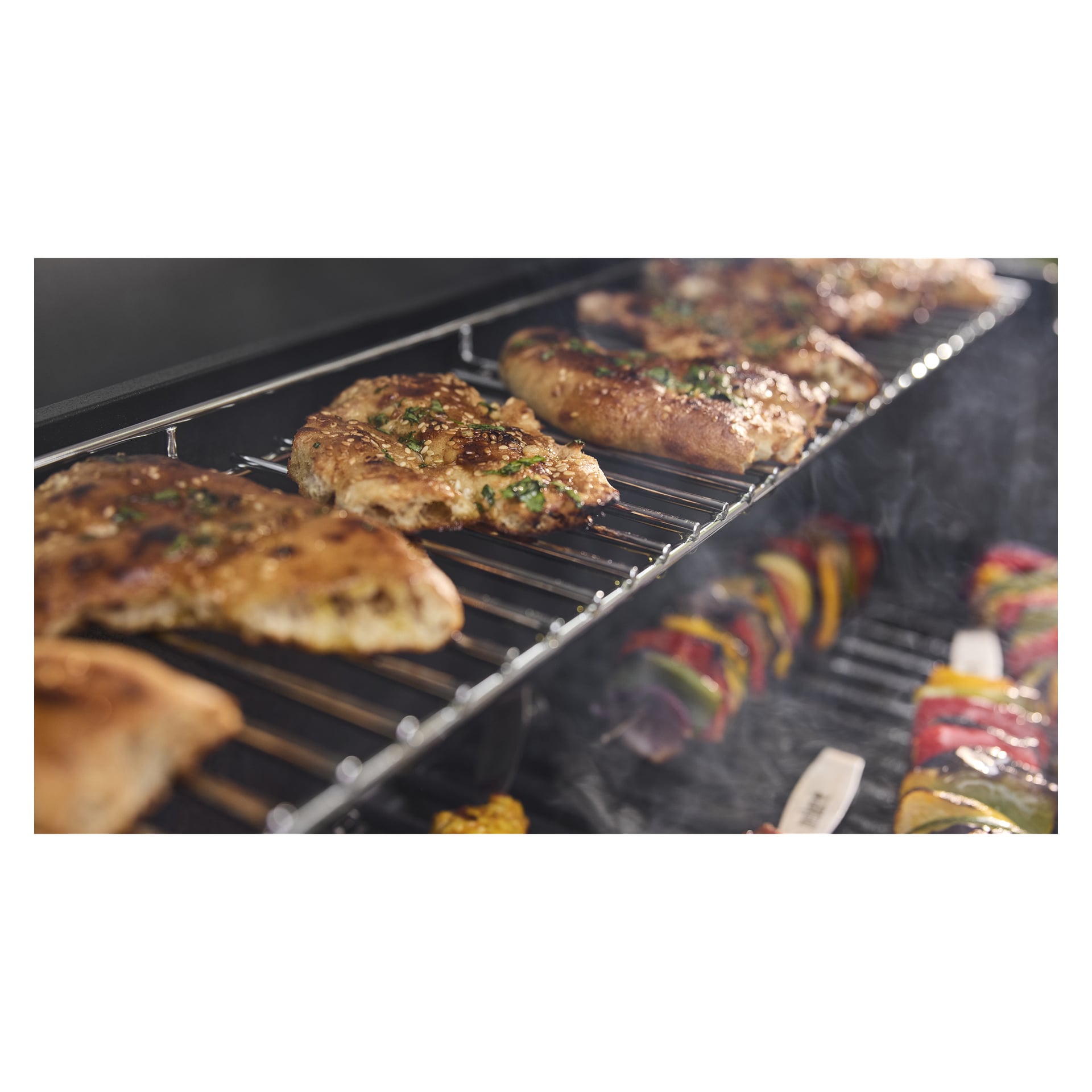 Piersi z kurczaka przyprawione ziołami grillowane są na górnej półce, a wędzone szaszłyki mięsa i warzyw smażą się pod grillem barbecue.