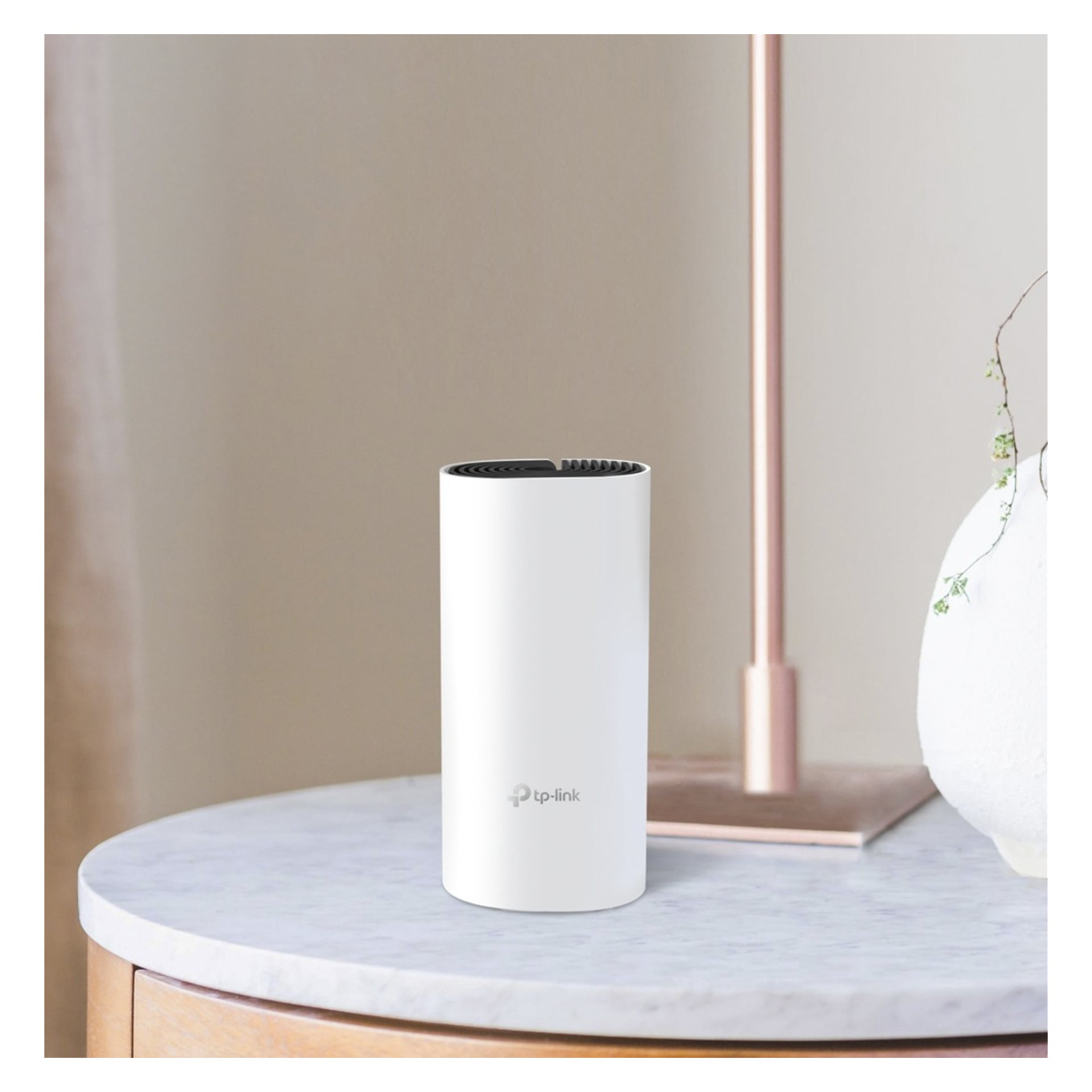 En vit TP-Link-enhet vilar på ett blekt runt bord bredvid en lampa och en liten växt i en vit vas, med en mjukt upplyst bakgrund.