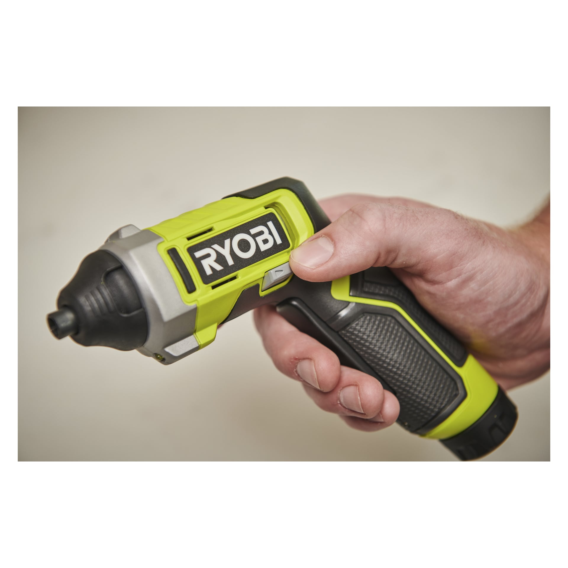 En hånd griper en Ryobi trådløs skrutrekker med svarte, grønne og sølvfargede farger med merkelappen tydelig vist.