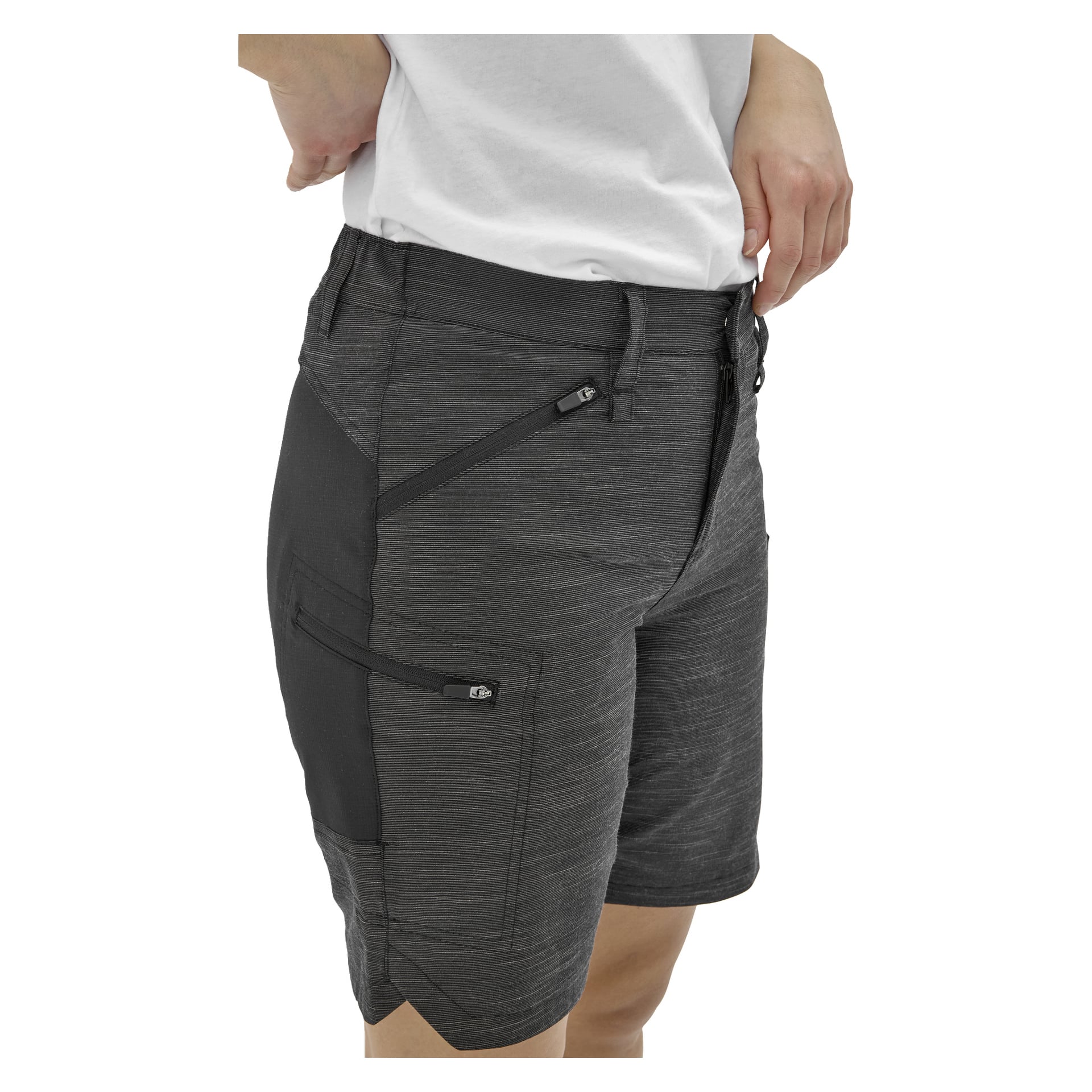 En person i vit skjorta och mörkgrå shorts poserar med ena handen på höften; Shortsen har fickor med dragkedja och svarta paneler.