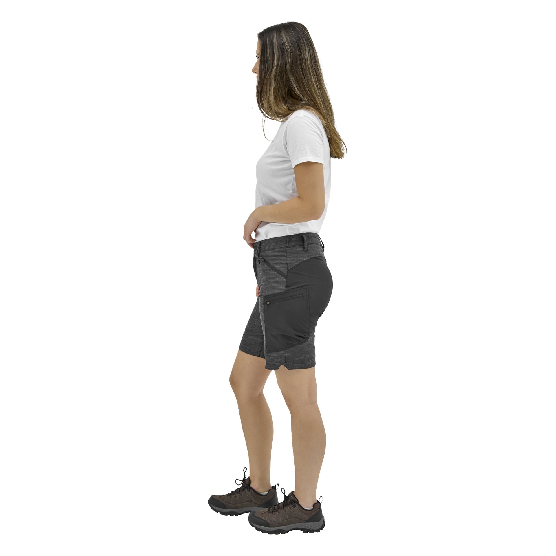 En kvinna i profil bär en vit t-shirt, mörkgrå shorts med sidofickor och svarta vandringsskor. Hennes långa hår är rakt.