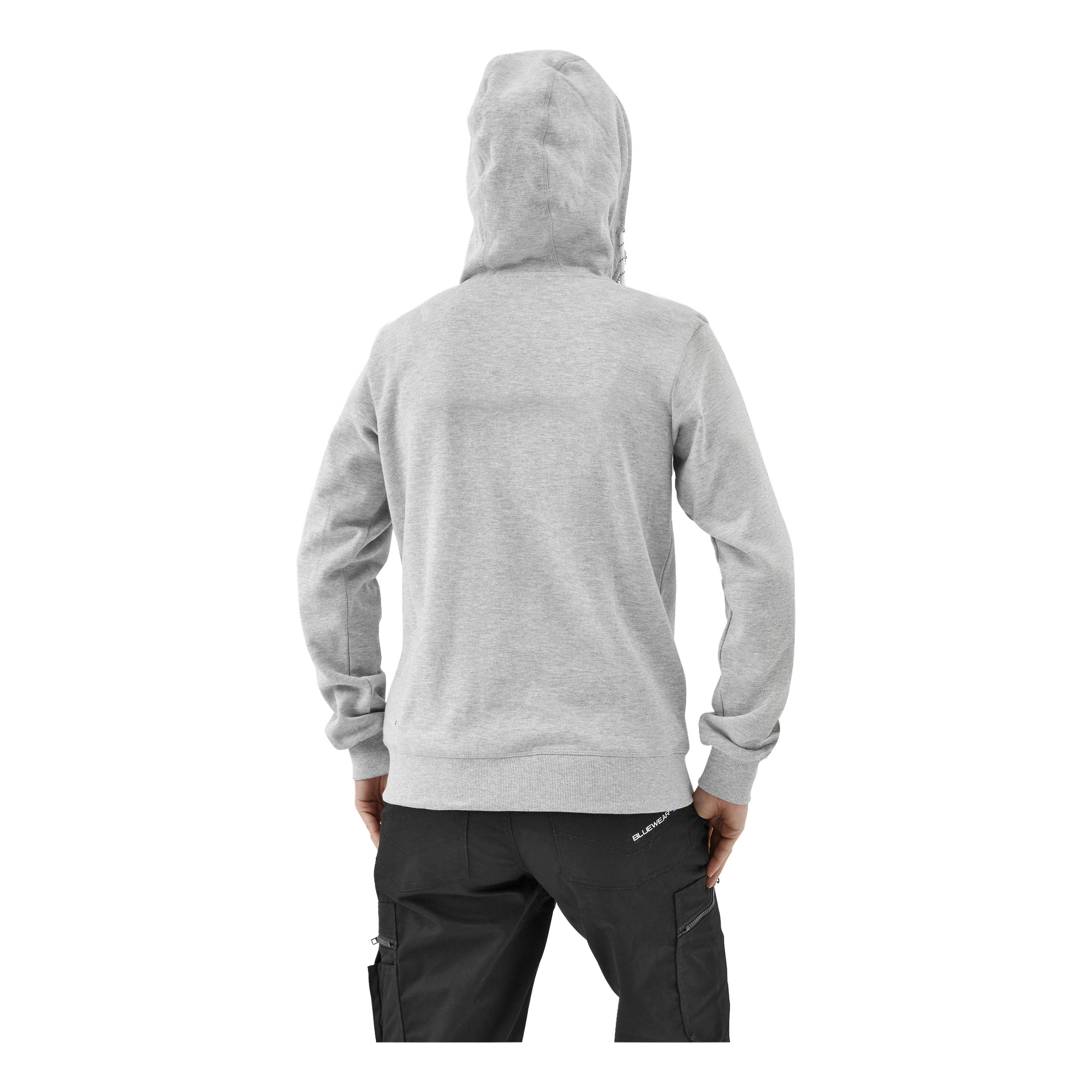 En person i en ljusgrå huvtröja och svarta cargobyxor står med ryggen mot kameran, höger hand på höften.
