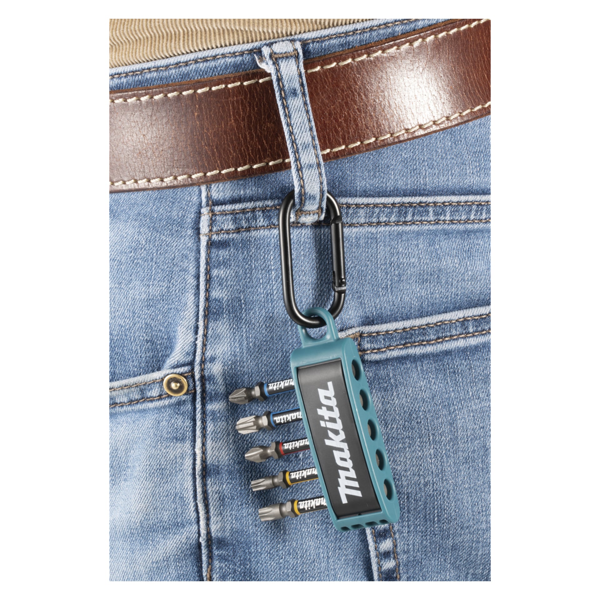 Närbild på någon i jeans och brunt bälte, bärande på en Makita-bitshållare och skruvmejselbitar på en svart karbinhake vid bältesöglan.